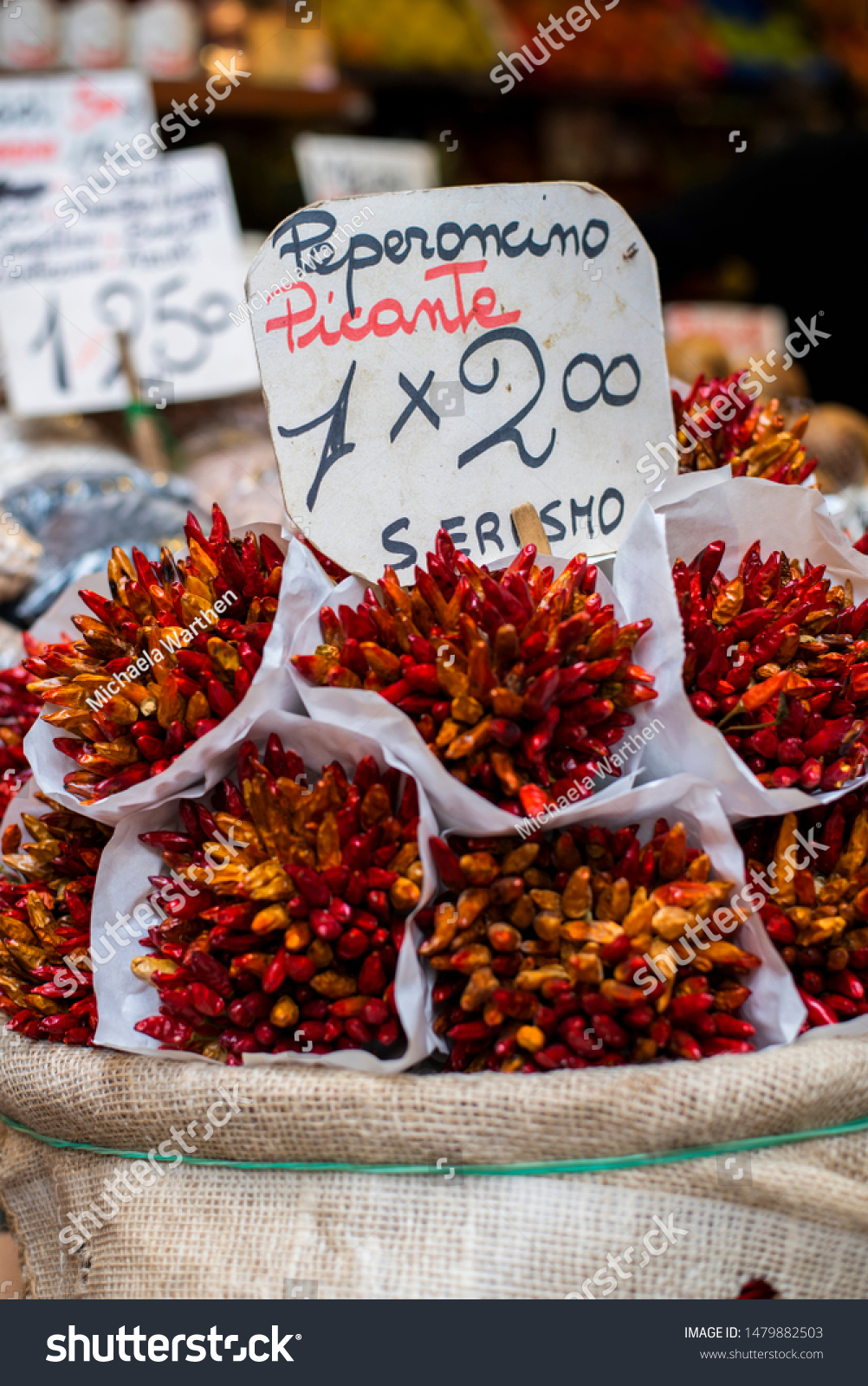 bunches of dried red hot chili peppers at an italian marketplace, peperoncino picante bouquet, dark red dried peppers #1479882503