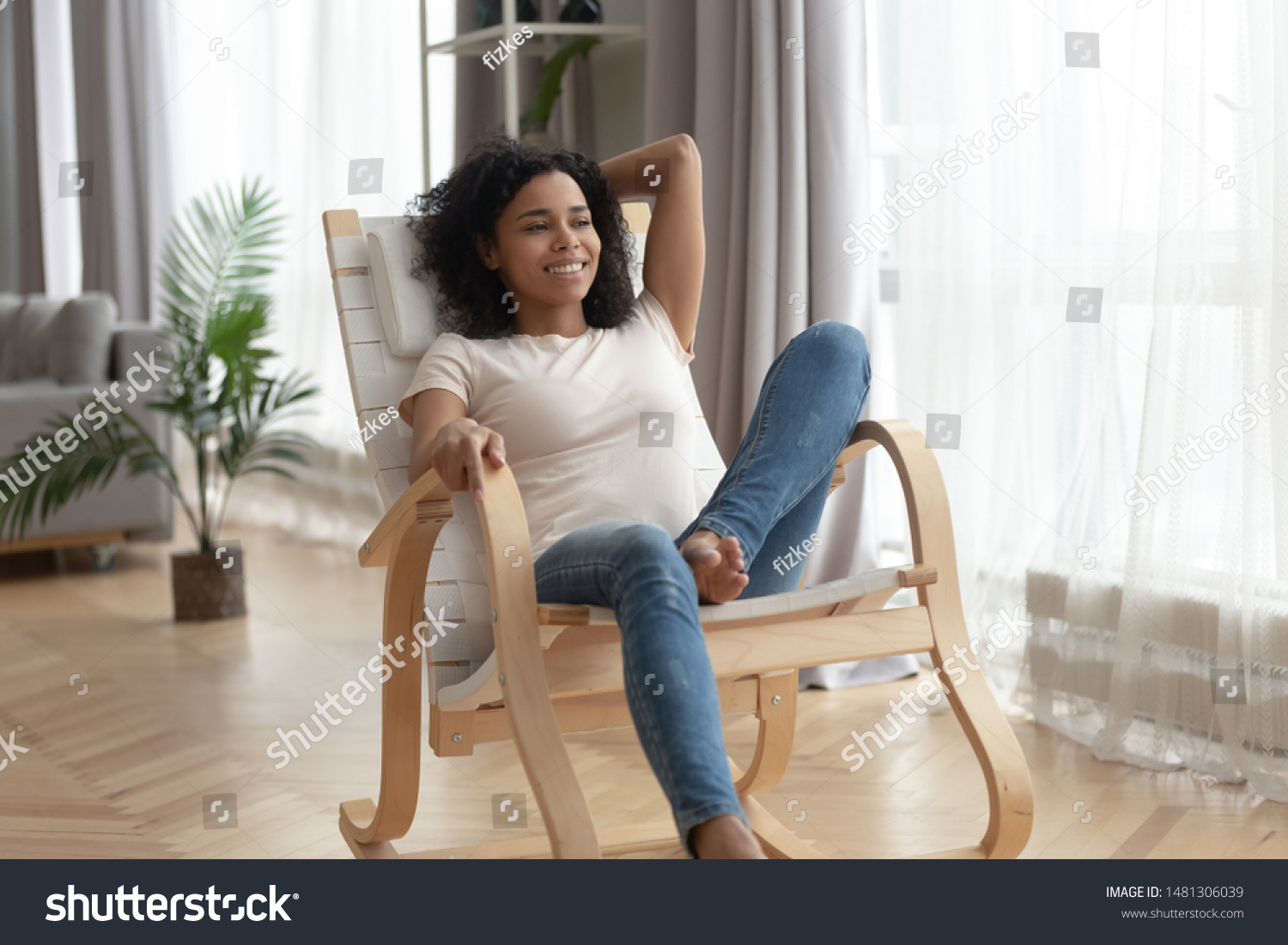 Smiling black biracial millennial girl sit rest in rocking chair look in distance thinking or memorizing, happy african american young woman relax in rocker at home spend weekend dreaming visualizing #1481306039