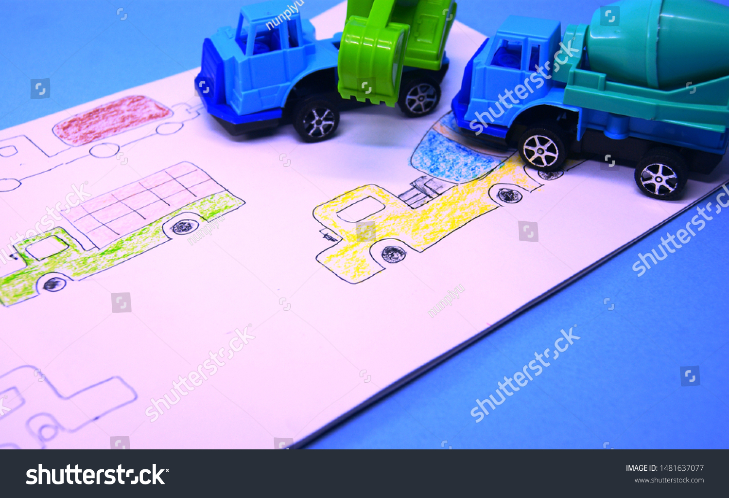 boy's drawing in drawing book and miniatures of excavator and concrete mixer truck #1481637077
