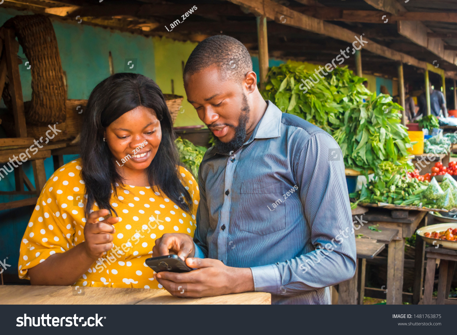 young black business agent meeting with a woman selling in a local market, showing her something on his phone #1481763875