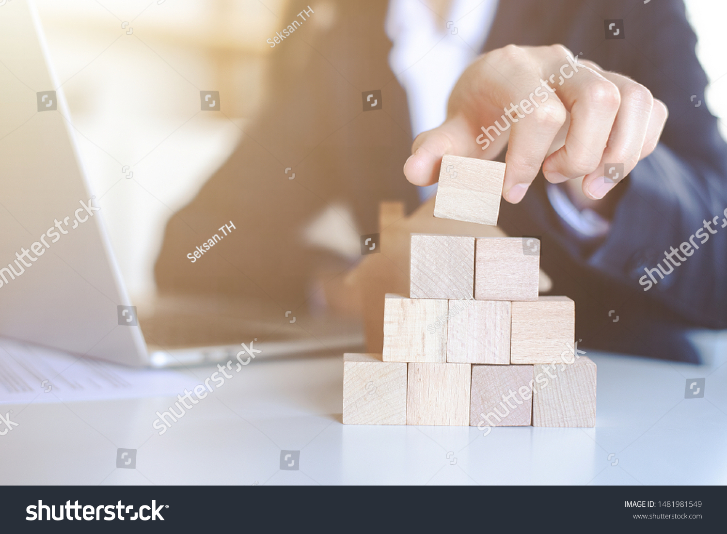 Closeup picture of a businessman placing wooden blocks to represent the peak of the boom to grow their business goals, financial statistics.
 #1481981549