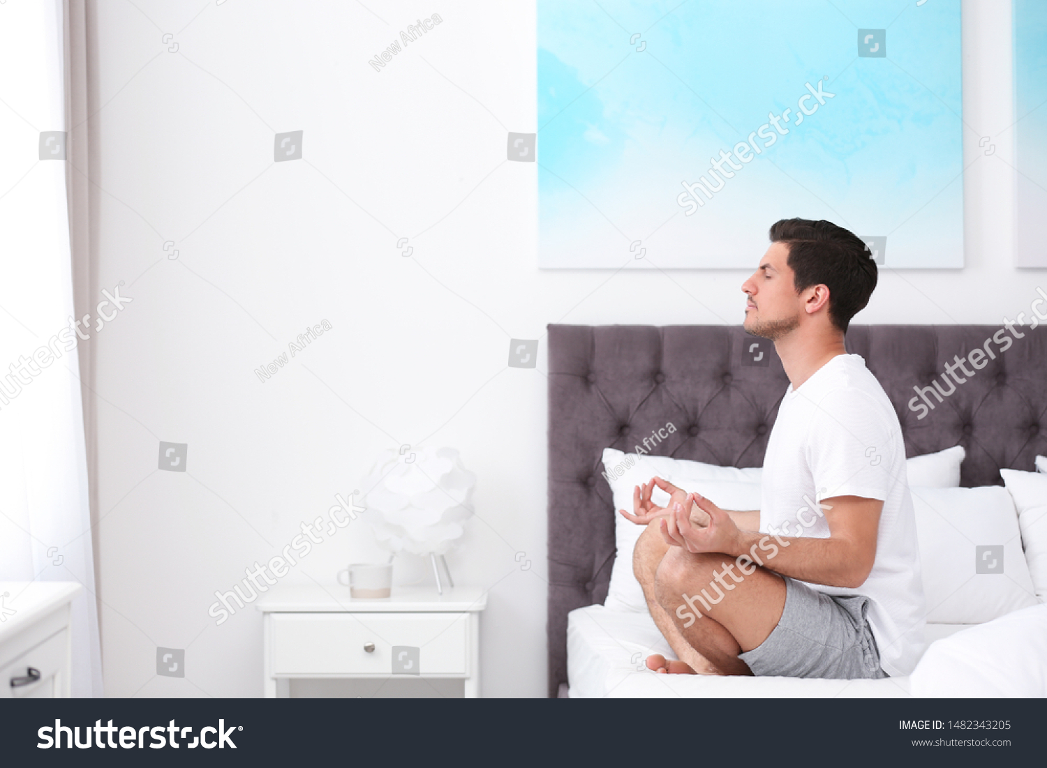 Man meditating on bed at home, space for text. Zen concept #1482343205