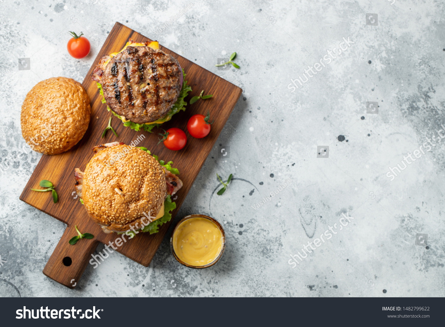 Tasty grilled home made burger with beef, tomato, cheese, bacon and lettuce on a light stone background with copy space. Top view. fast food and junk food concept. Flat lay #1482799622