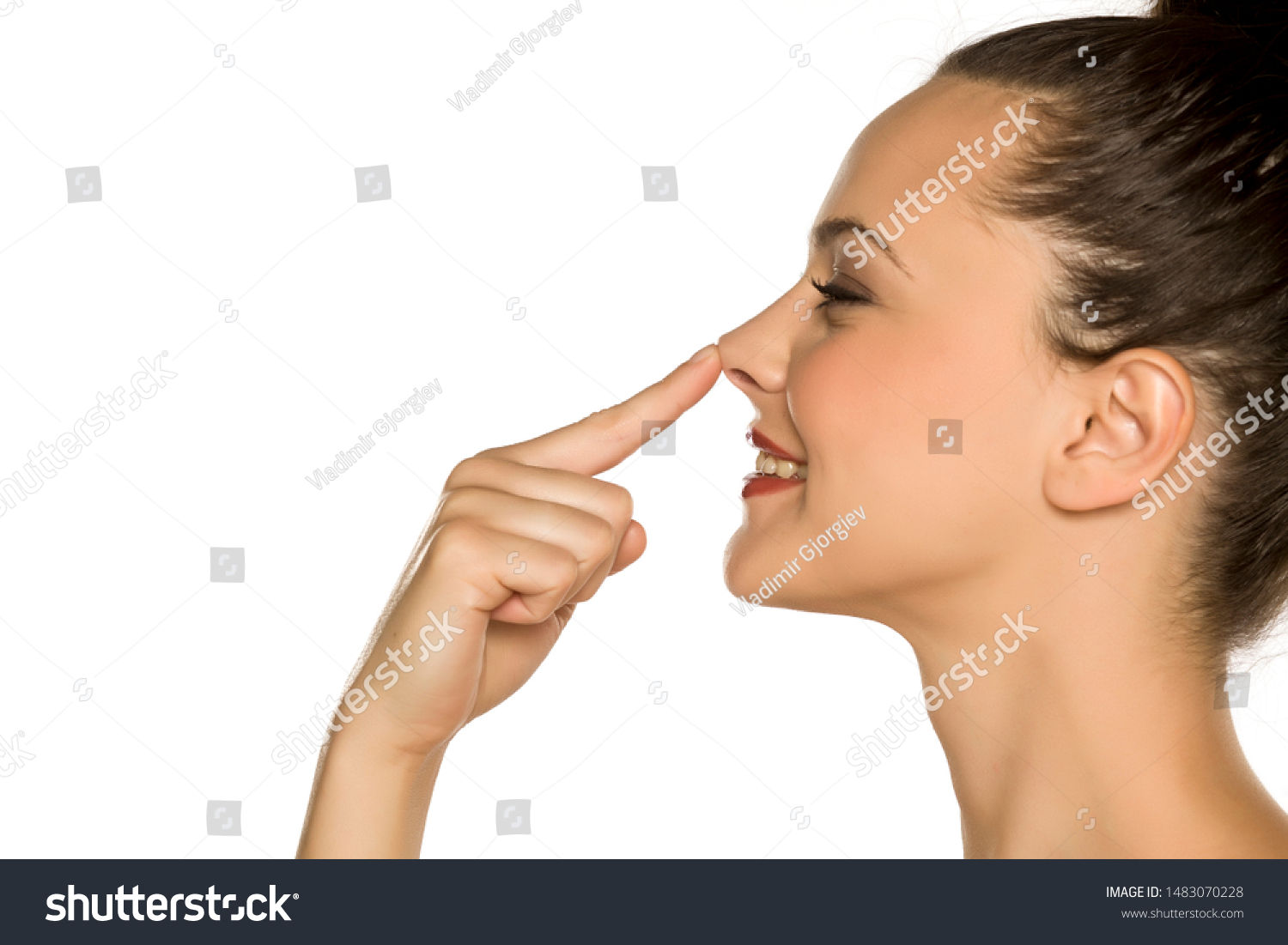 profile of young happy woman touches her nose with her finger on a white background #1483070228