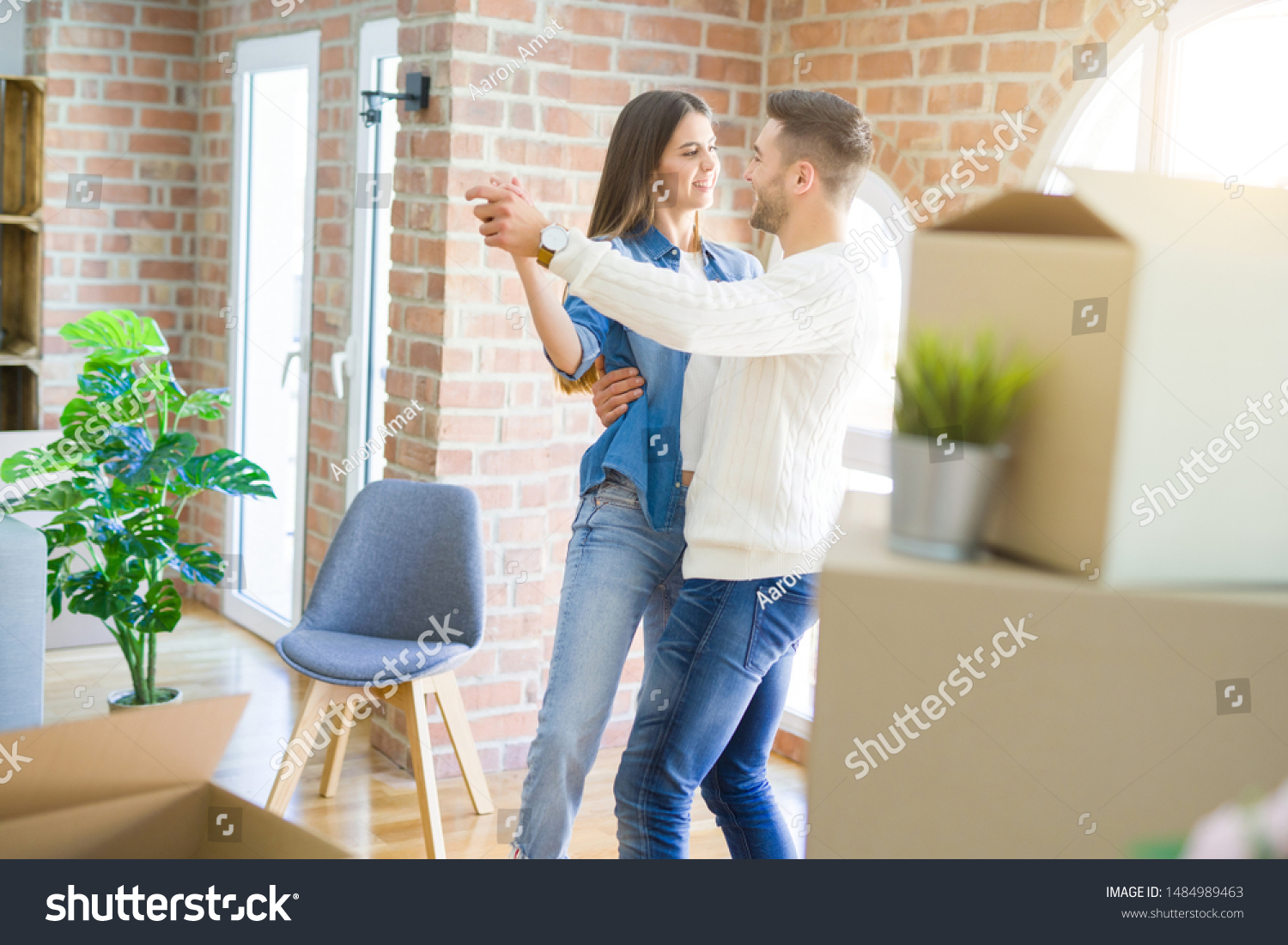 Beautiful young couple moving to a new home, dancing in love celebrating new apartment #1484989463