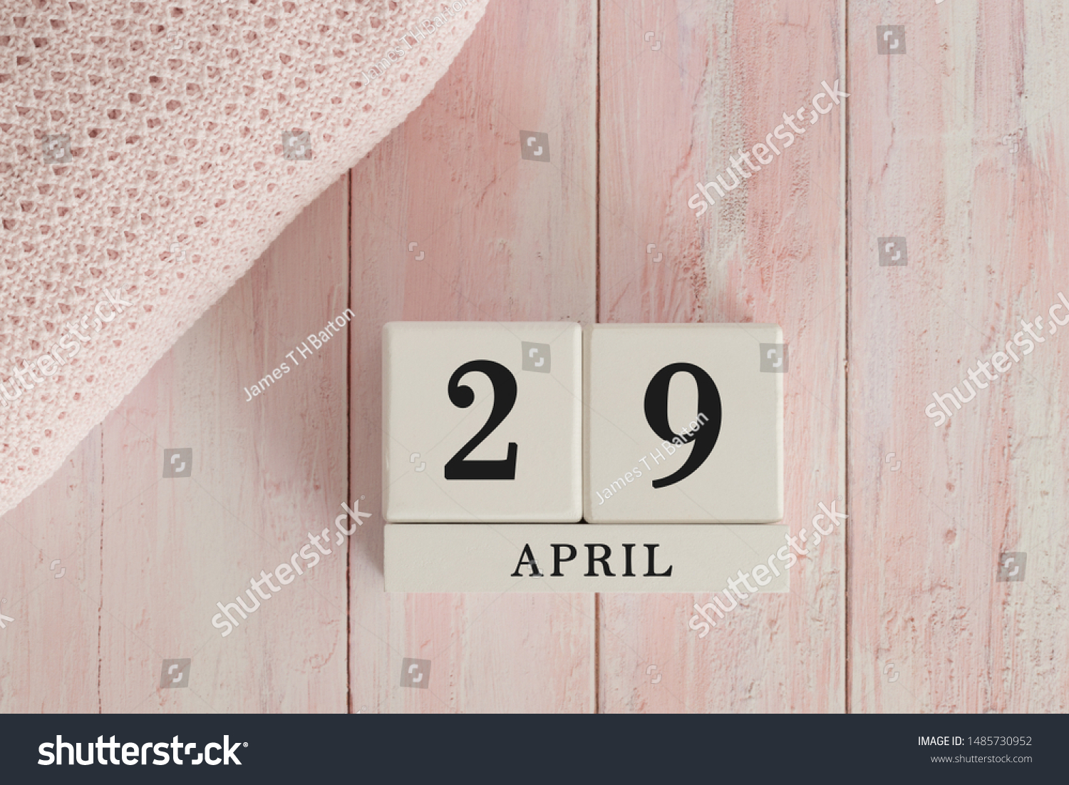 29 April Date on Cubes. Date on painted pink wood, next to baby blanket. Theme of baby due dates and birth dates. #1485730952