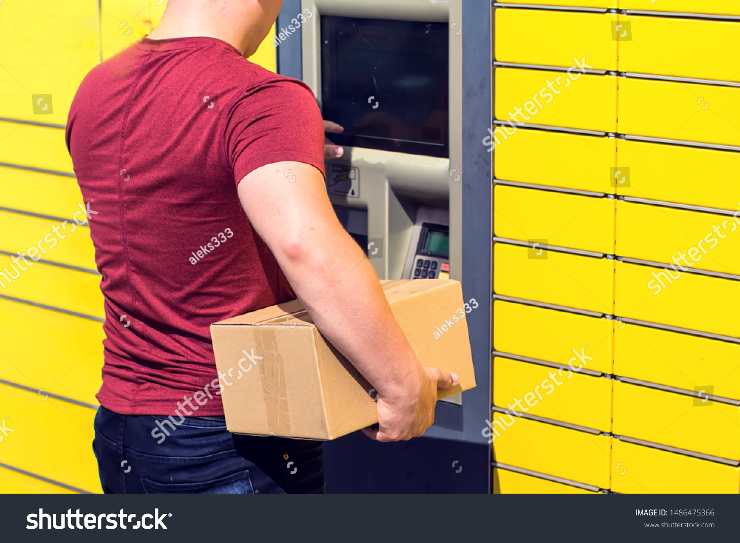 Man using automated self-service post terminal machine or locker to depisit a parcel for storage #1486475366
