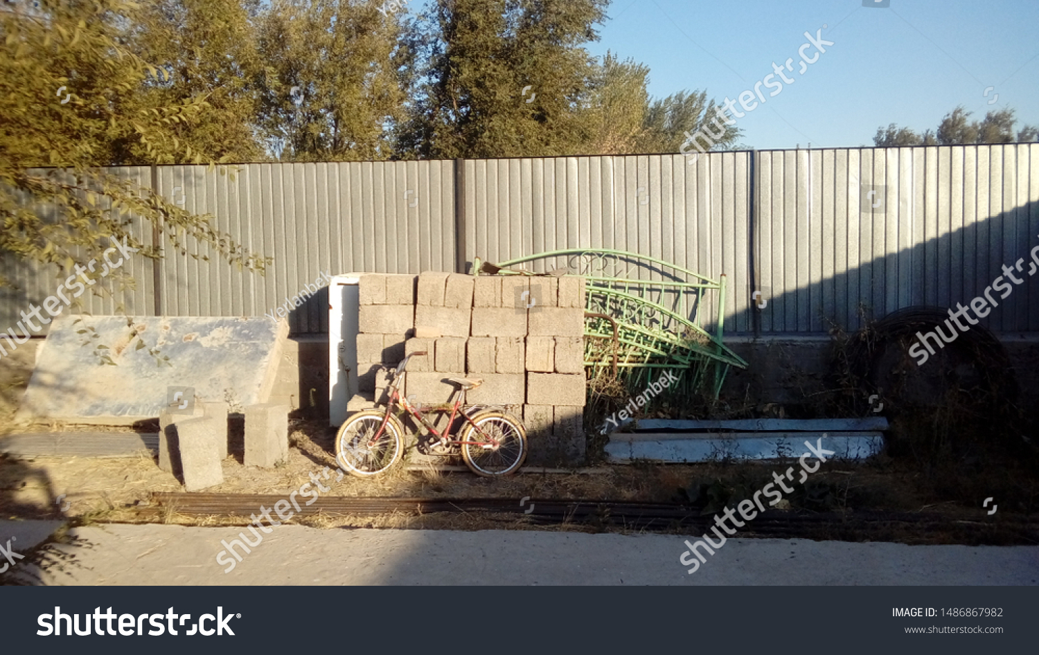 A typical aul yard from the inside. At the fence of corrugated board, a bicycle and miscellaneous utensils #1486867982