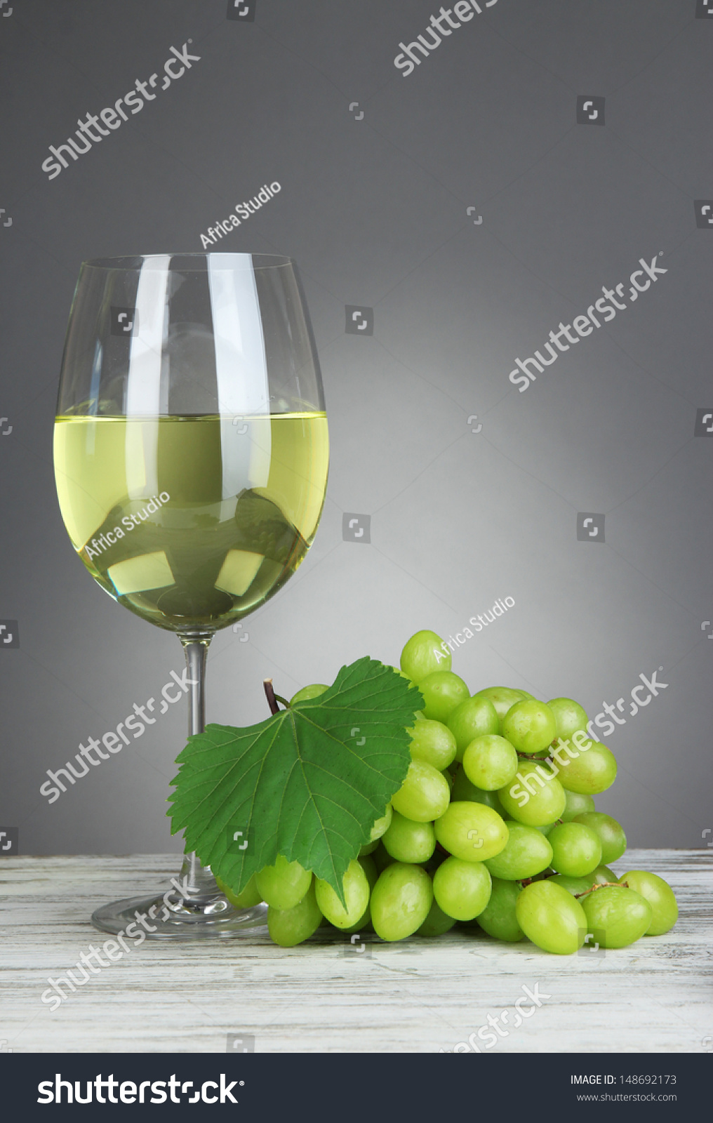 Ripe delicious grapes with glass of wine on table on gray background #148692173