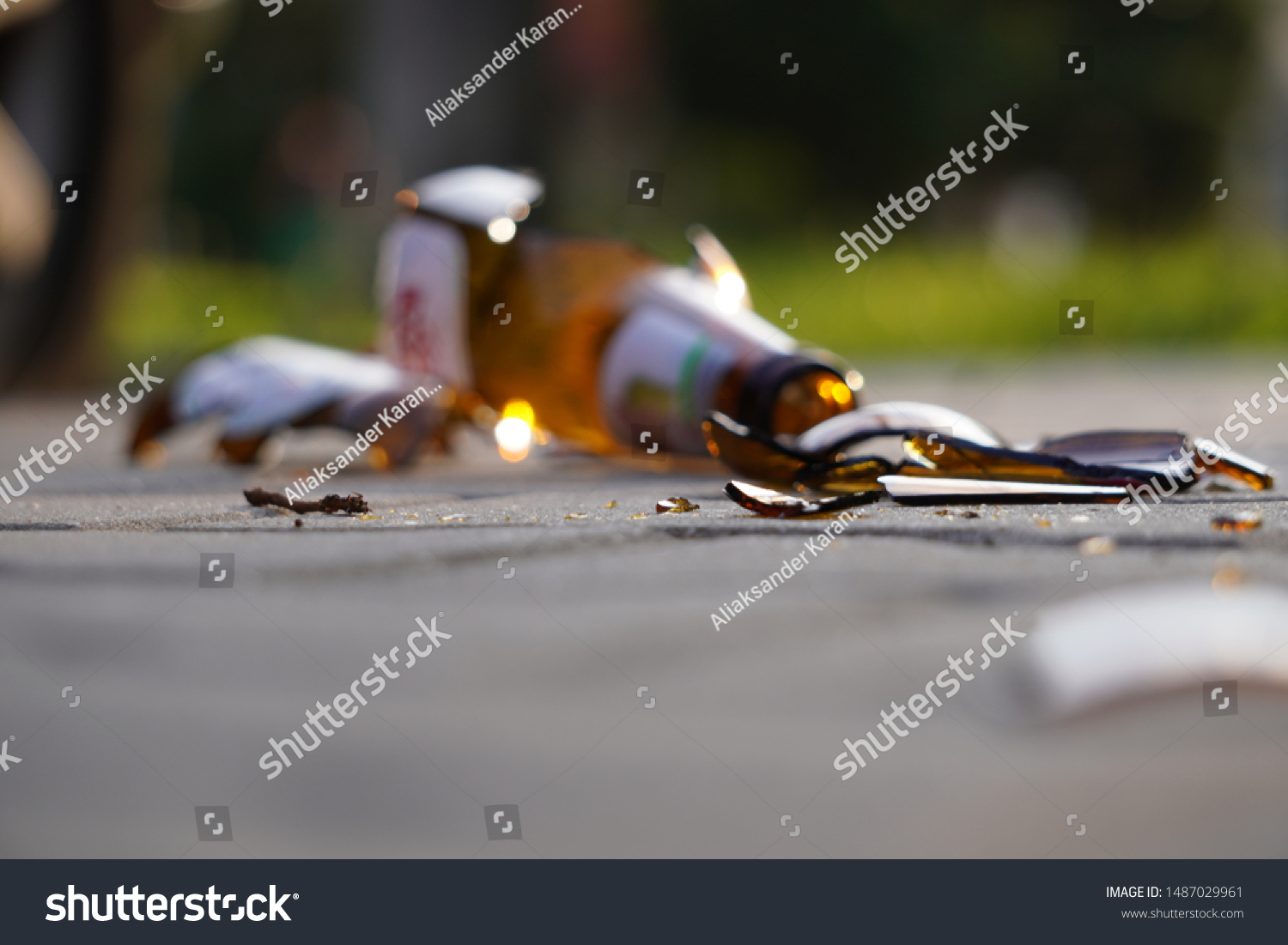 bottle of beer, soda or drugs from dark glass is broken. Shattered beer bottle on ground in sunset light. Fragments of glass on asphalt. Texture, background, wallpaper. #1487029961