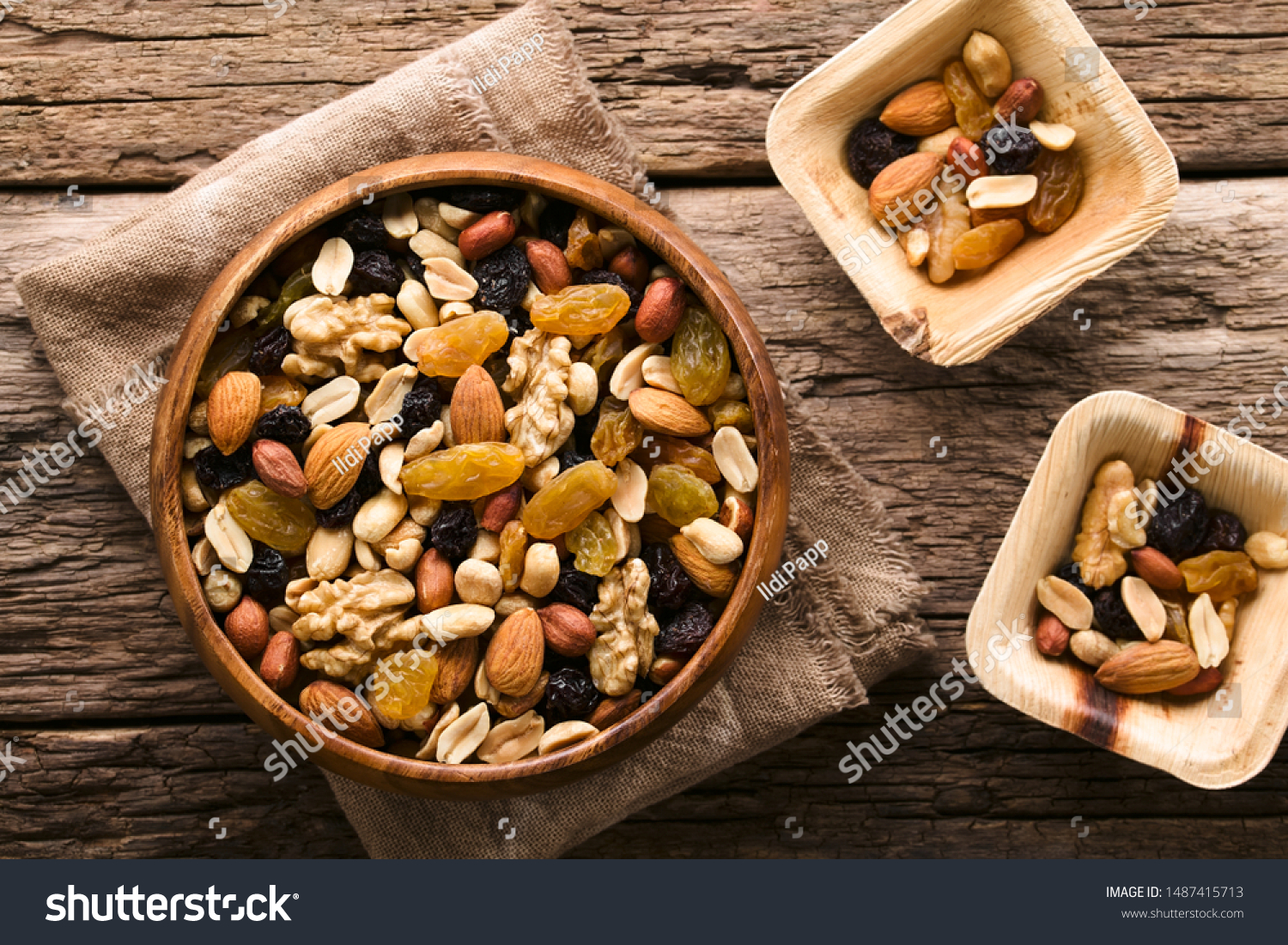 Healthy trail mix snack made of nuts (walnut, almond, peanut) and dried fruits (raisin, sultana) in wooden bowl, photographed overhead (Selective Focus, Focus on the trail mix in the big bowl) #1487415713