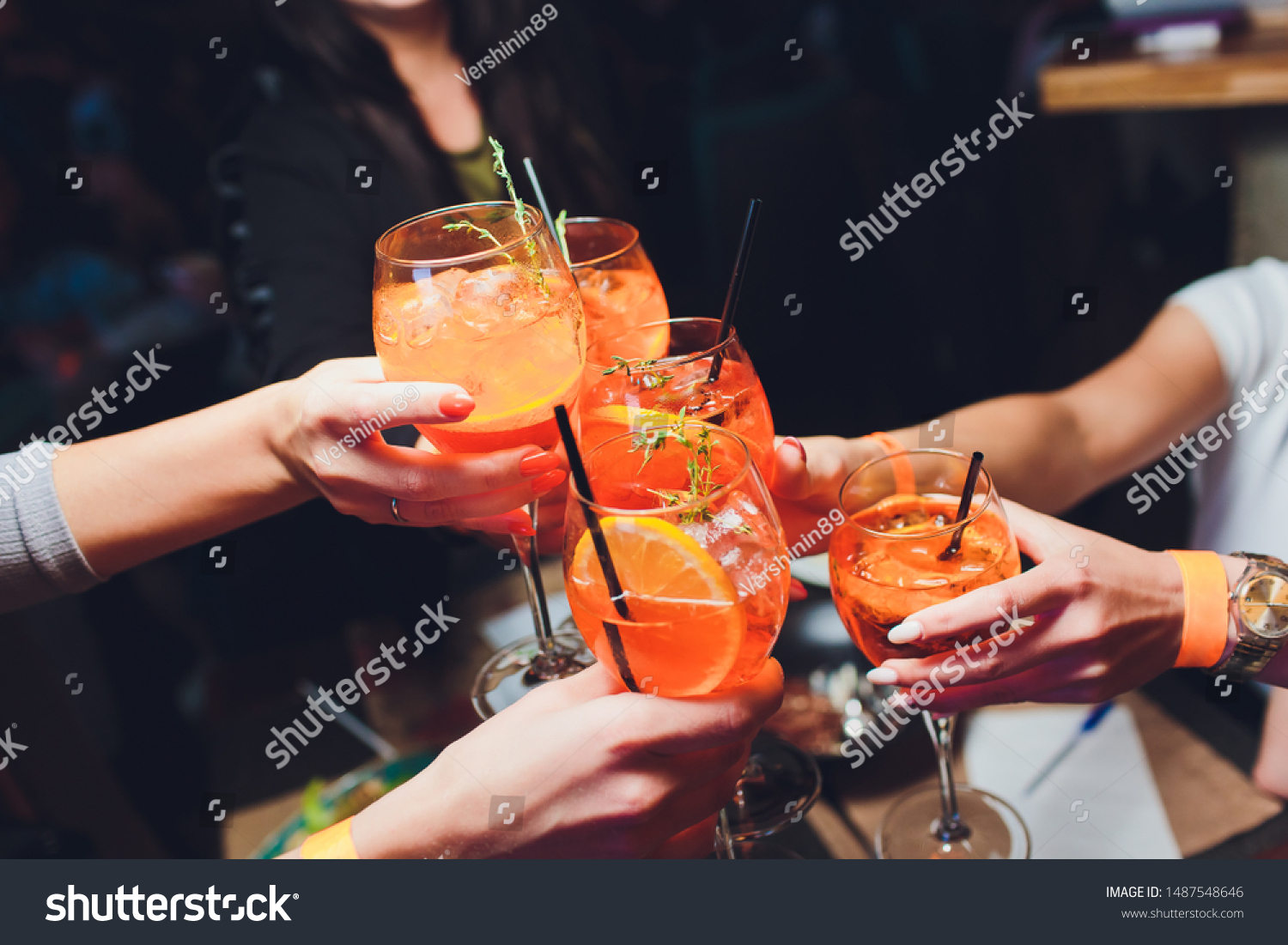 women raising a glasses of aperol spritz at the dinner table. #1487548646