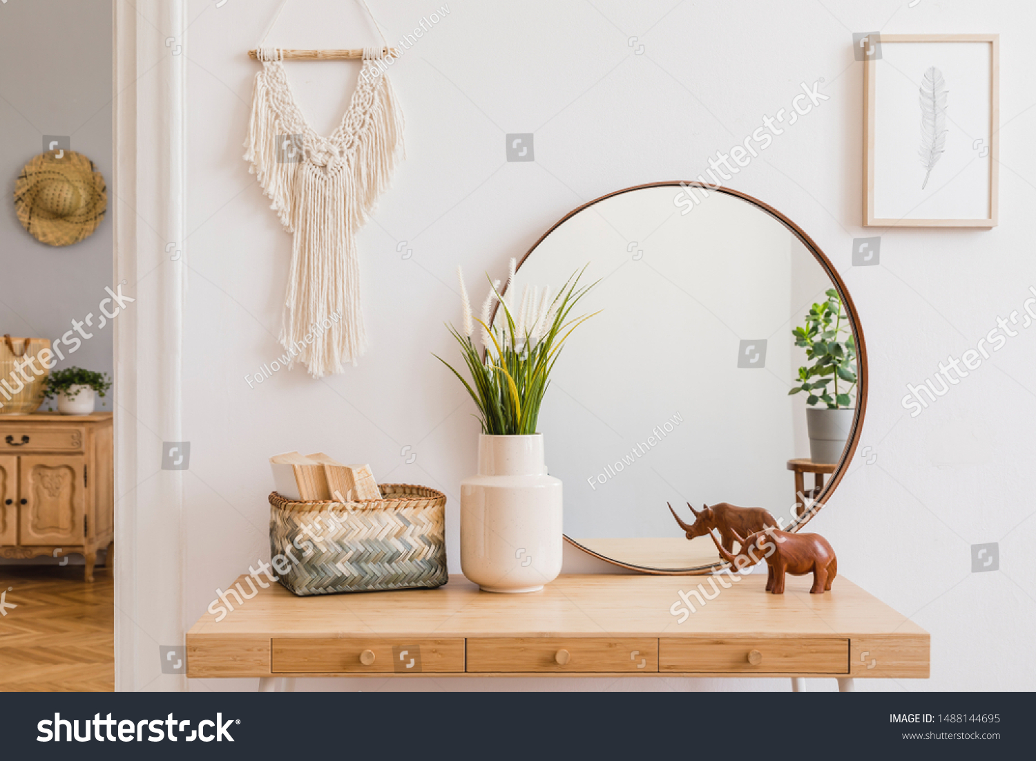 Sunny boho interiors of apartment with mirror, dressing table, furnitures, flowers, plants, rattan box, books, sculpture, macrame and design accessories. Stylish home decor of open space. Template. #1488144695