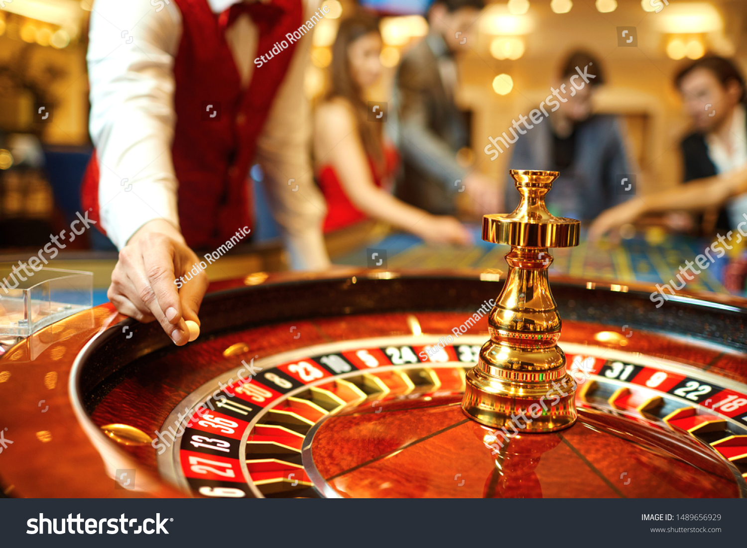 The croupier holds a roulette ball in a casino in his hand. #1489656929