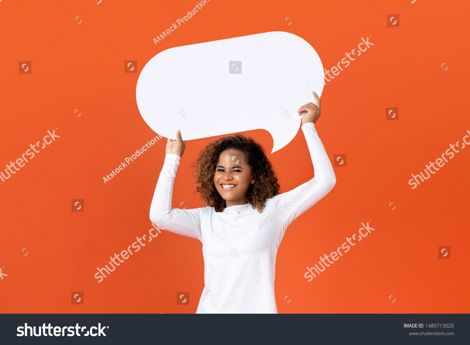 Happy young African American woman in plain white long sleeve t-shirt holding empty speech bubble isolated on orange  background #1489713020