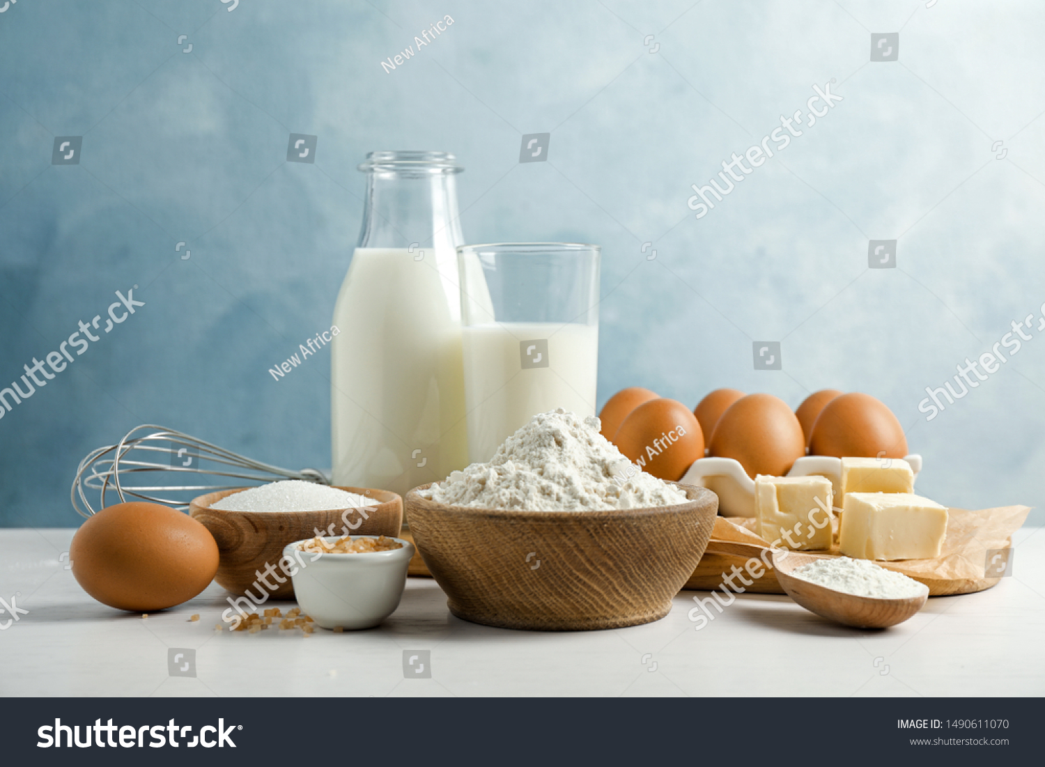Fresh ingredients for delicious homemade cake on white wooden table against blue background #1490611070