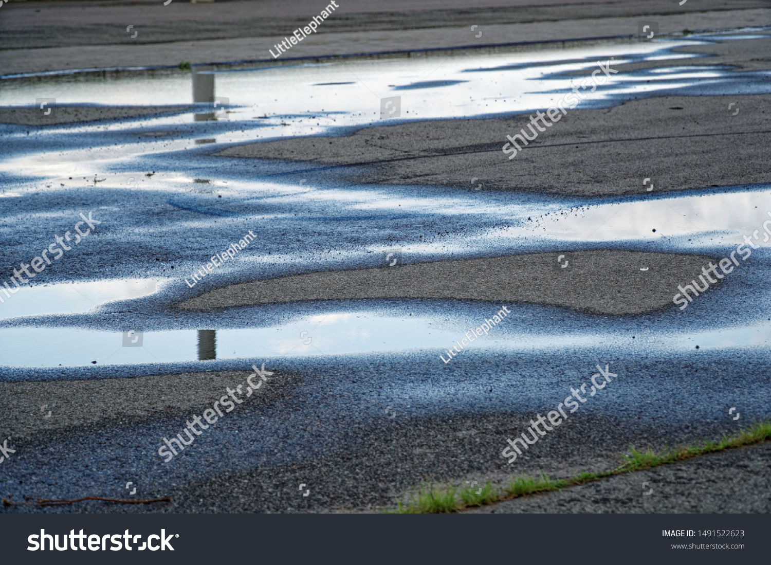 Sky reflected in a puddle of water on pavement, Early morning sunrise #1491522623