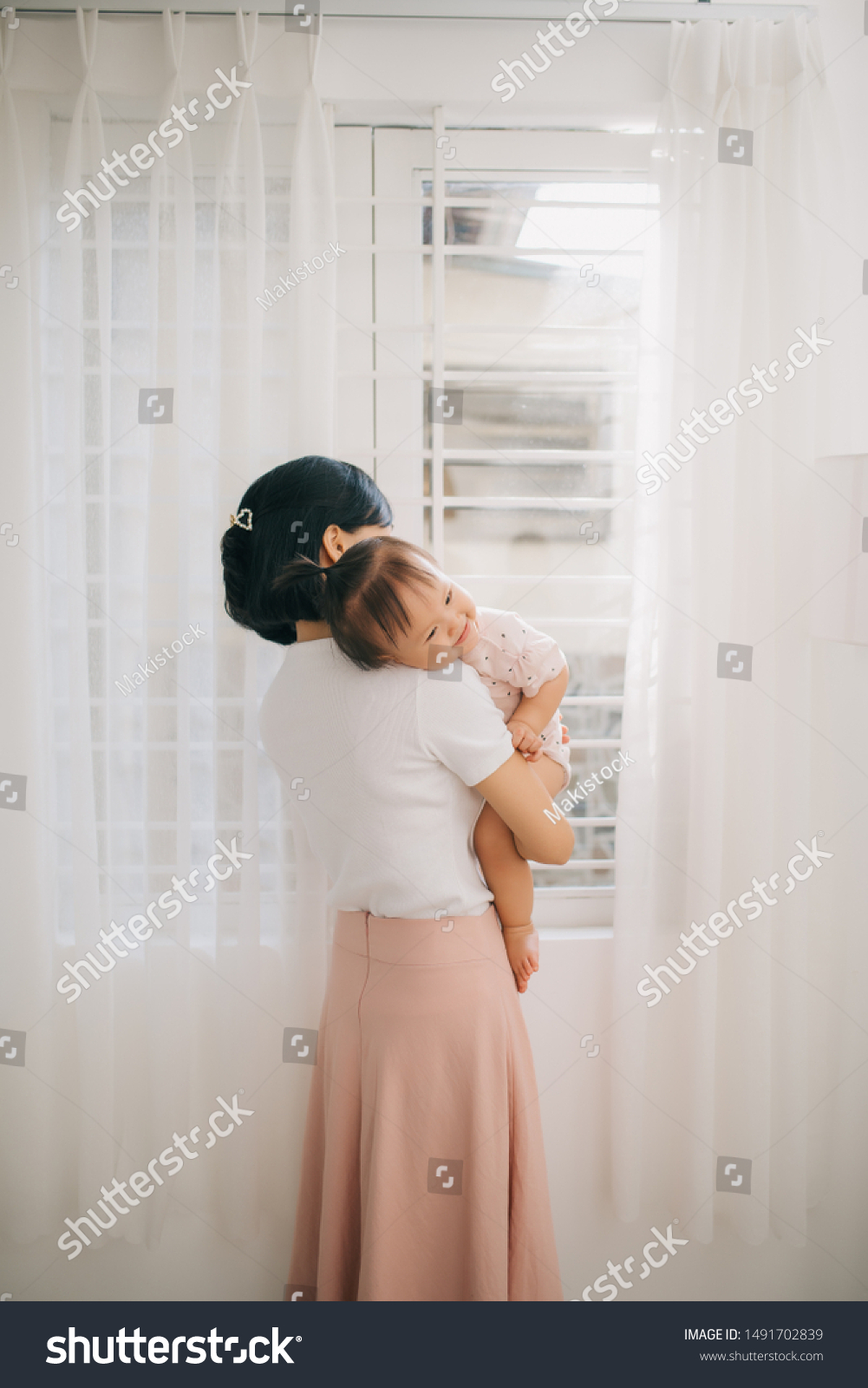 Portrait of happy vietnamese mother hugging with her cute little daughter at home #1491702839