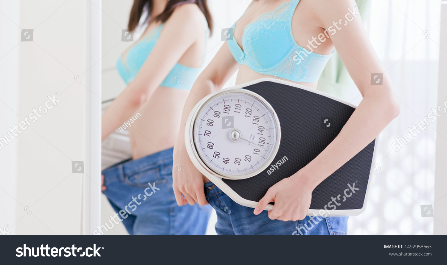Girl lose weight successfully and show her big jean before in front of mirror with scale #1492958663