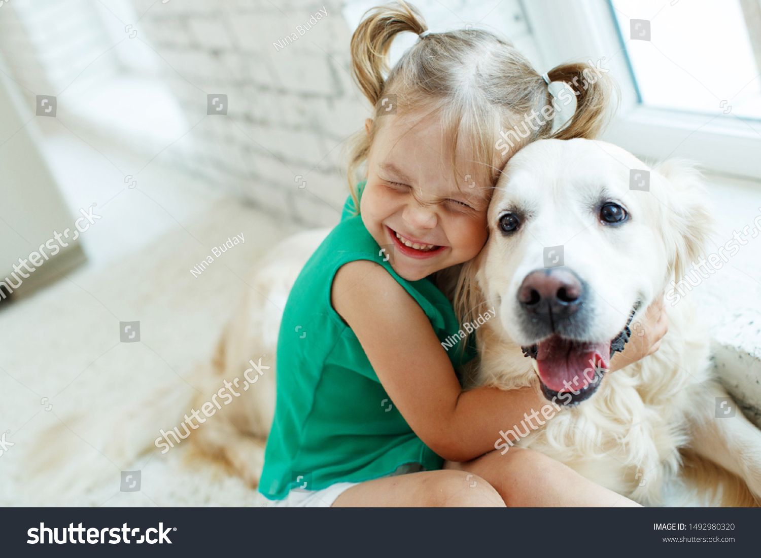 A child with a dog. Girl with a Labrador at home.  #1492980320
