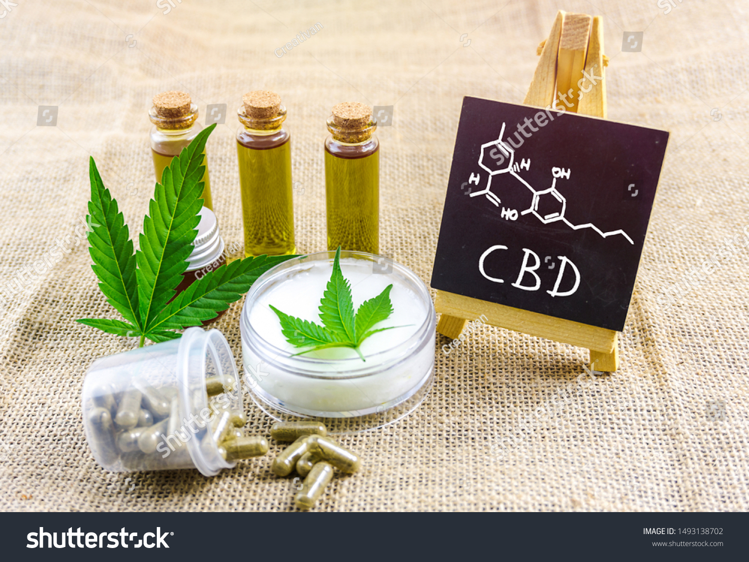 Full spectrum CBD and THC cannabis oils, pills and cbd lotion on hemp cloth with chemical structure on blackboard #1493138702