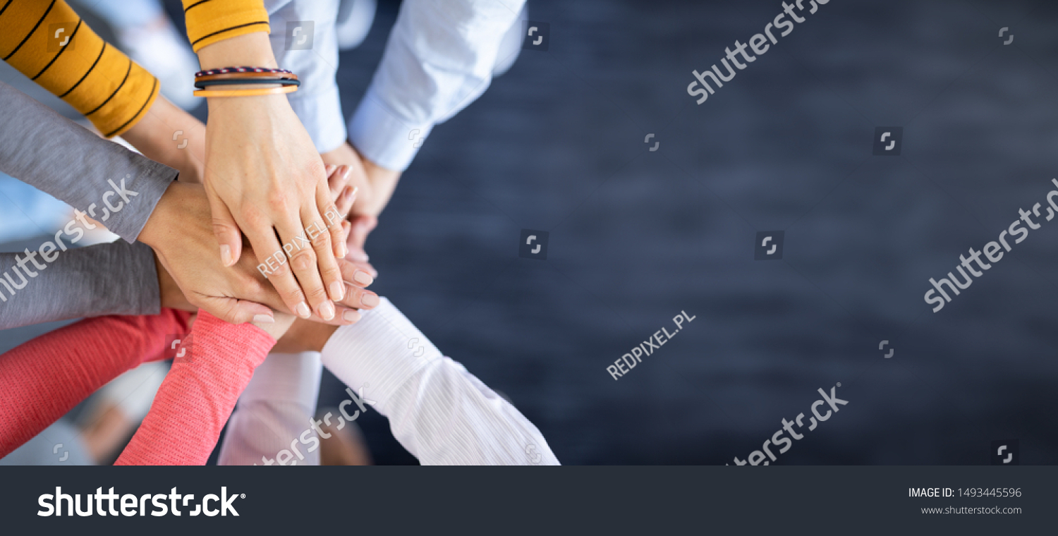 Close up top view of young business people putting their hands together. Stack of hands. Unity and teamwork concept. #1493445596