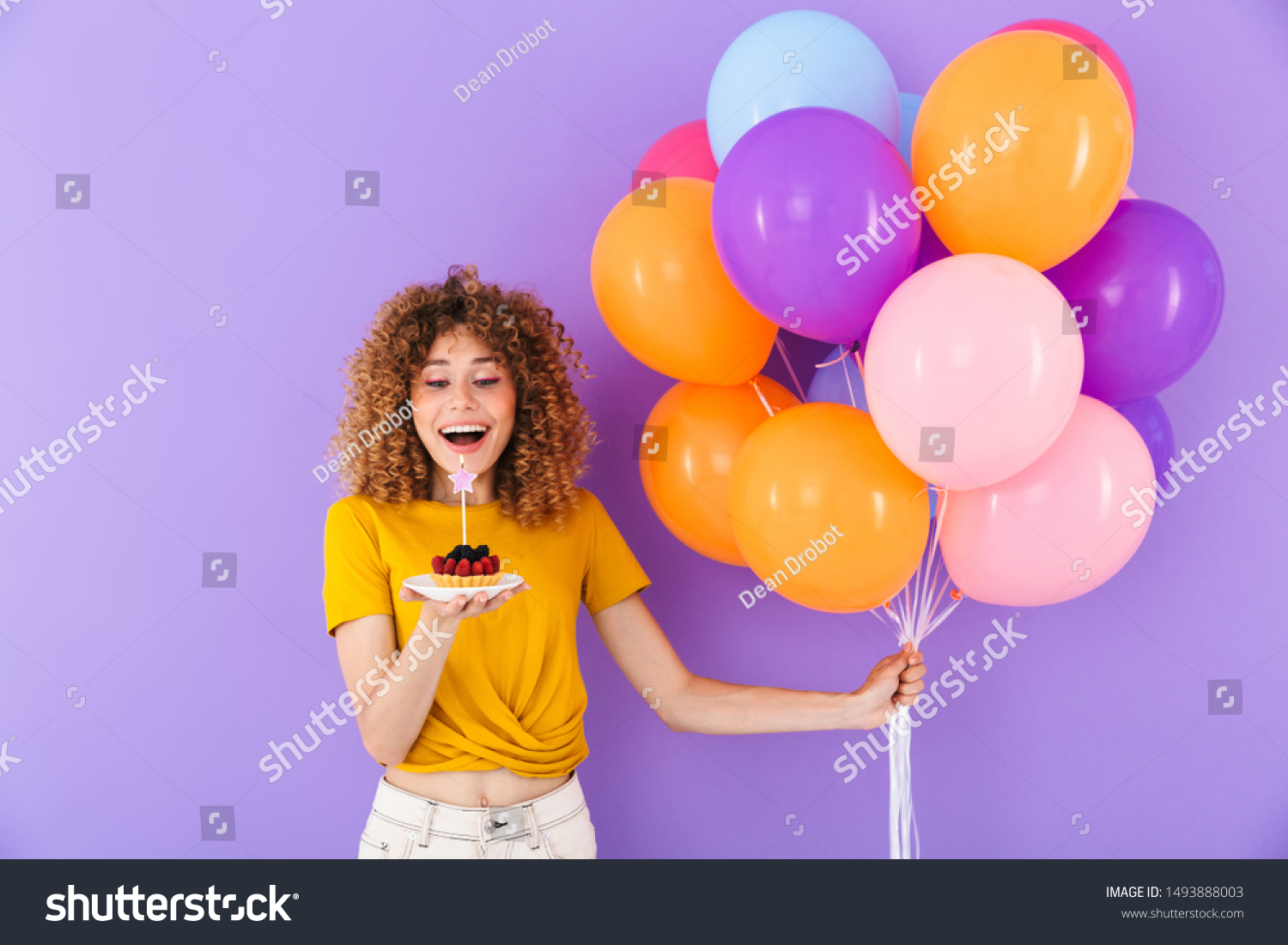 Image of happy young woman celebrating birthday with multicolored air balloons and piece of pie isolated over violet background #1493888003