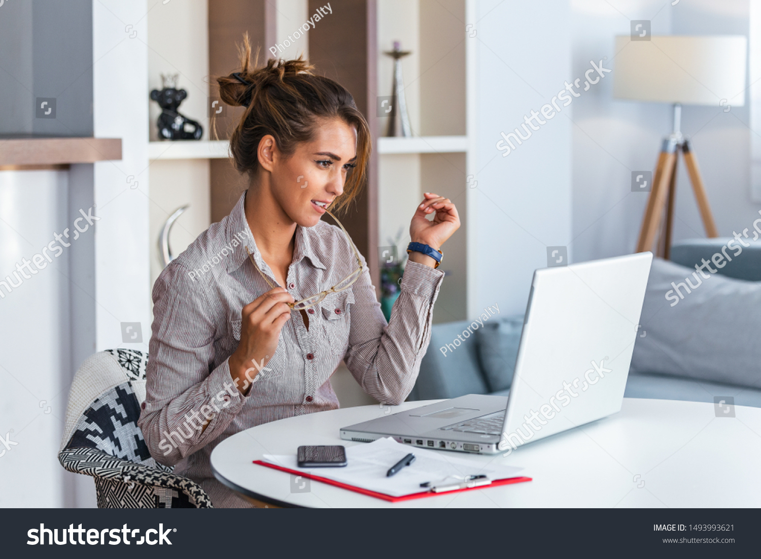 Young business woman biting eyeglasses and looking at her laptop. #1493993621