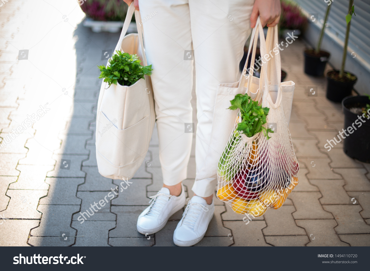 Girl is holding mesh shopping bag and cotton shopper with vegetables without plastic bags at farmers market. Zero waste, plastic free concept. Sustainable lifestyle. Banner #1494110720