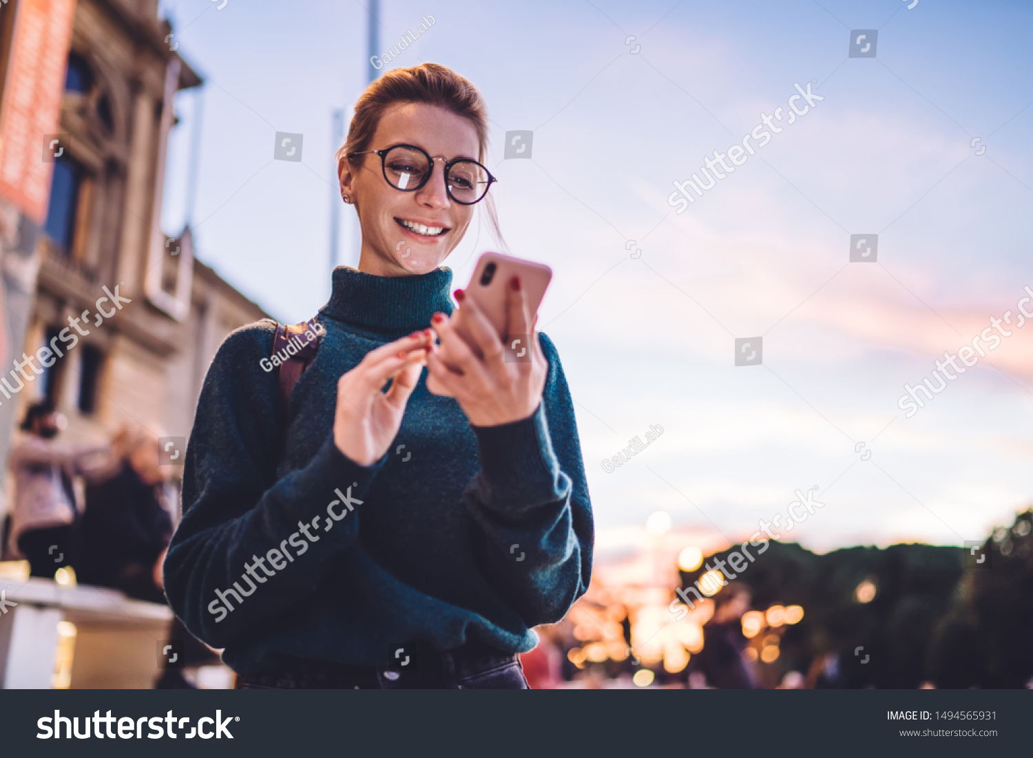Cheerful hipster girl reading pleasant text message from best friend connected to public internet outdoors, happy woman with beautiful smile chatting on cell smartphone while relaxing outdoors #1494565931
