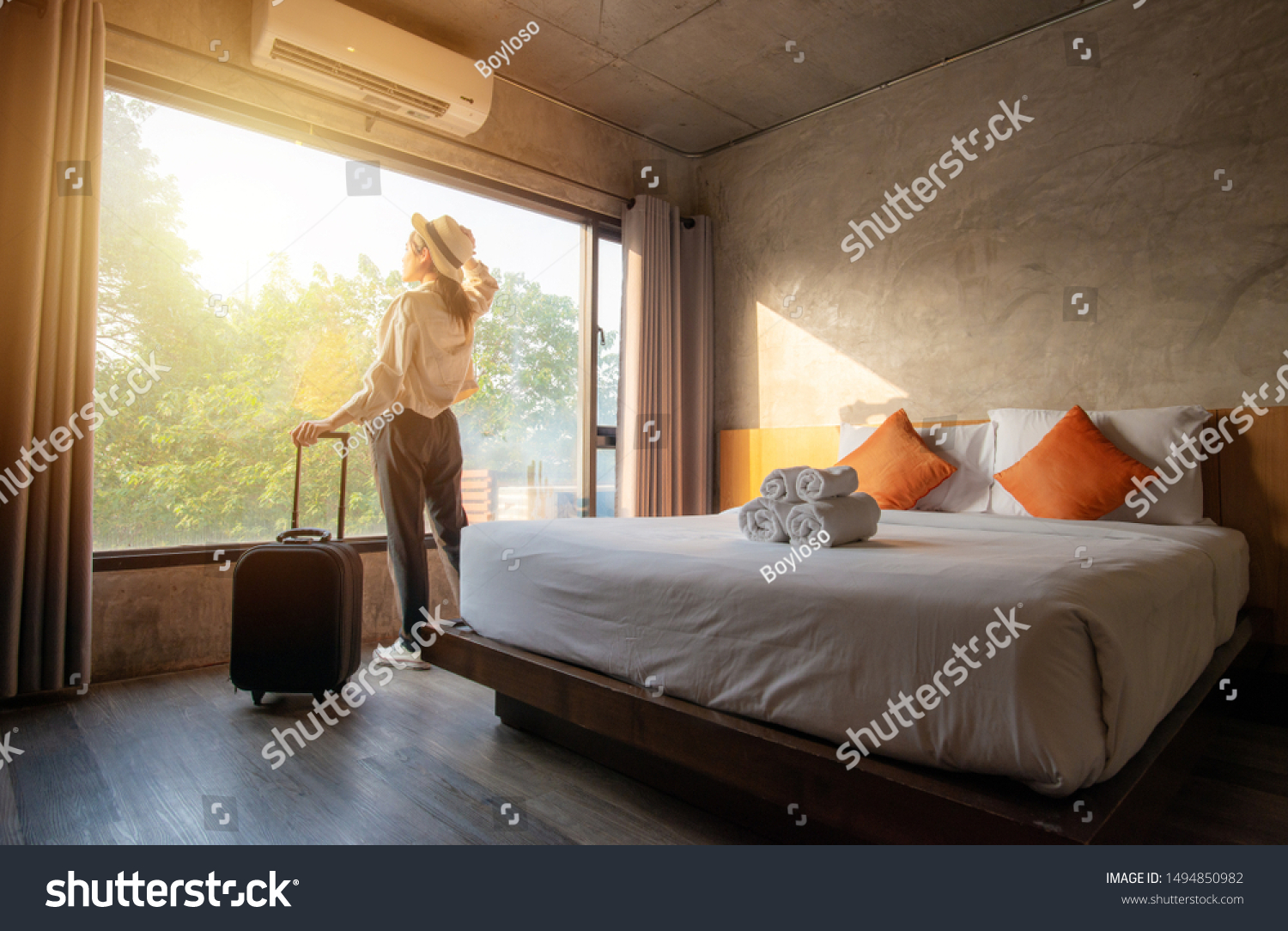 Portrait of tourist woman standing nearly window, looking to beautiful view with her luggage in hotel bedroom after check-in. Conceptual of travel and vacation. #1494850982