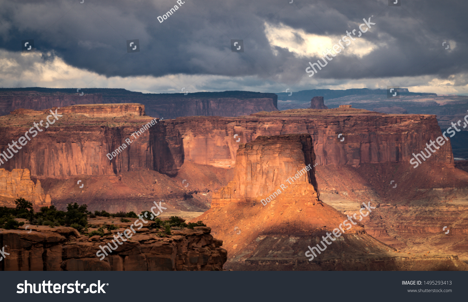 Beautiful sunlight peeking out from storm clouds. The red rock formations come alive as the sunlight hits their surface. The scene creates a sense of awe and wonder. #1495293413