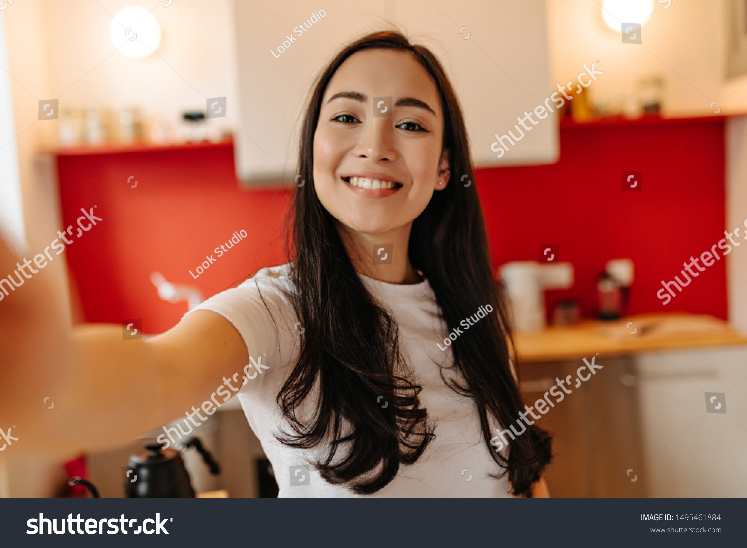 Woman in great mood takes selfie in kitchen. Portrait of brown-eyed girl #1495461884