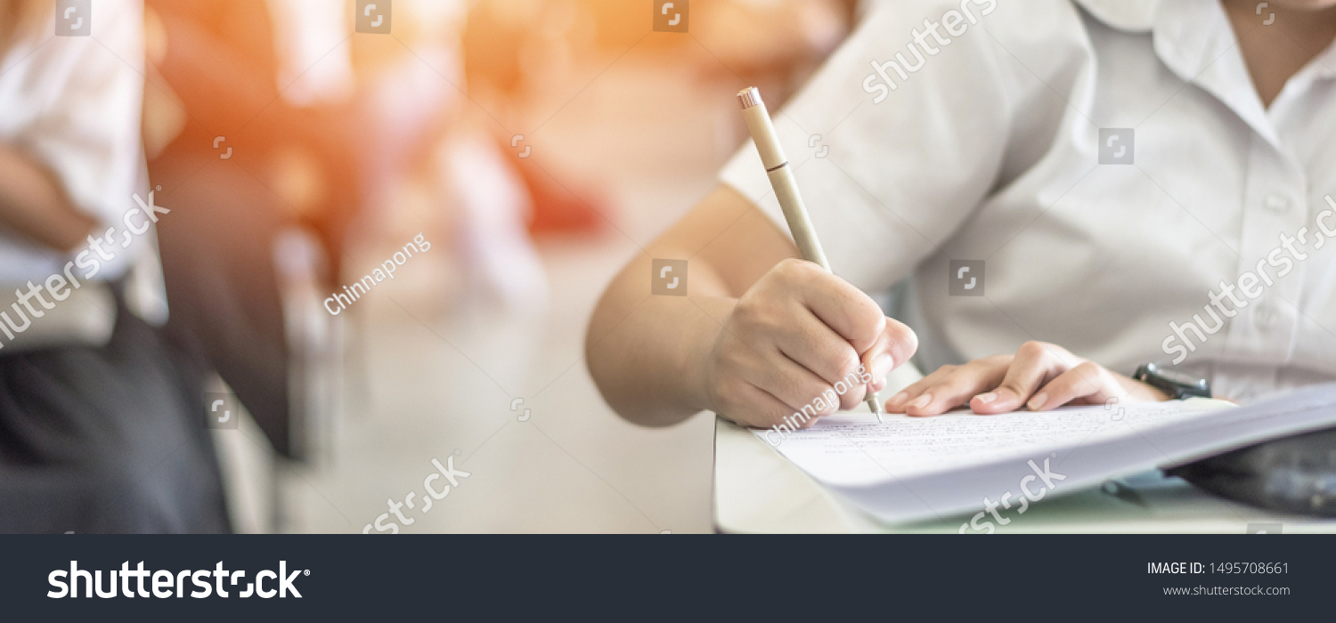 Exam at school with student's taking educational admission test in class, thinking hard, writing answer in university classroom, education and world literacy day concept #1495708661