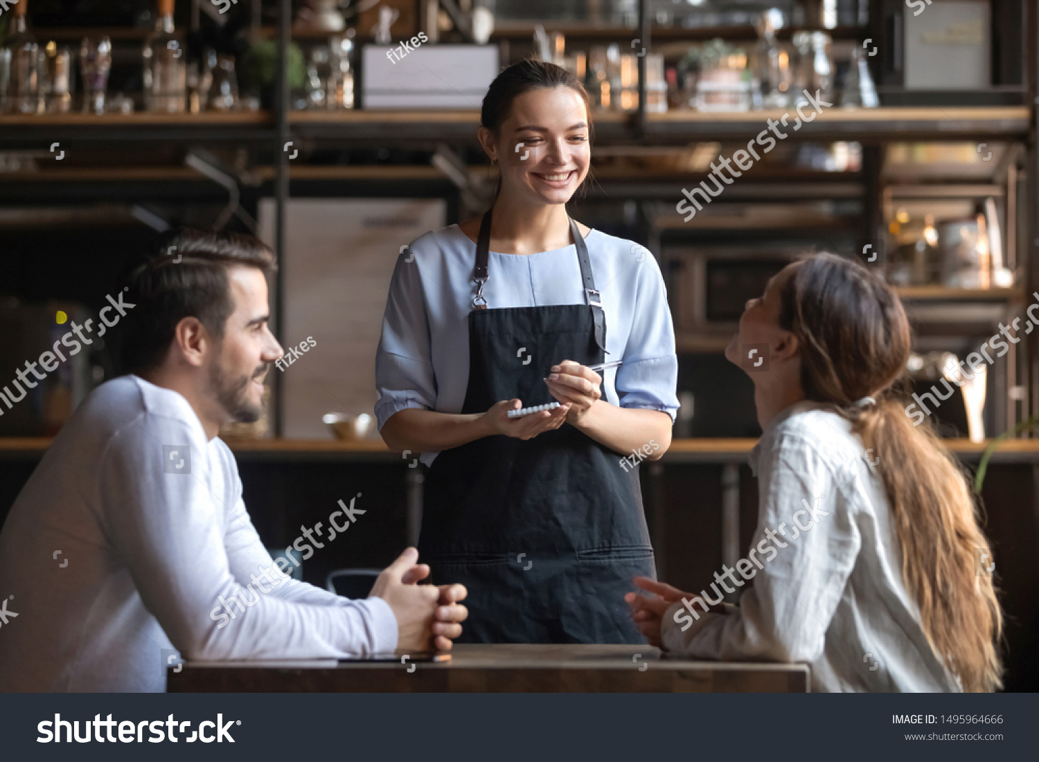 Smiling waitress wear apron hold notepad pen take order talk to clients serving restaurant guests couple choosing food drinks menu sit at cafe coffeehouse table, waiting staff, good customer service #1495964666