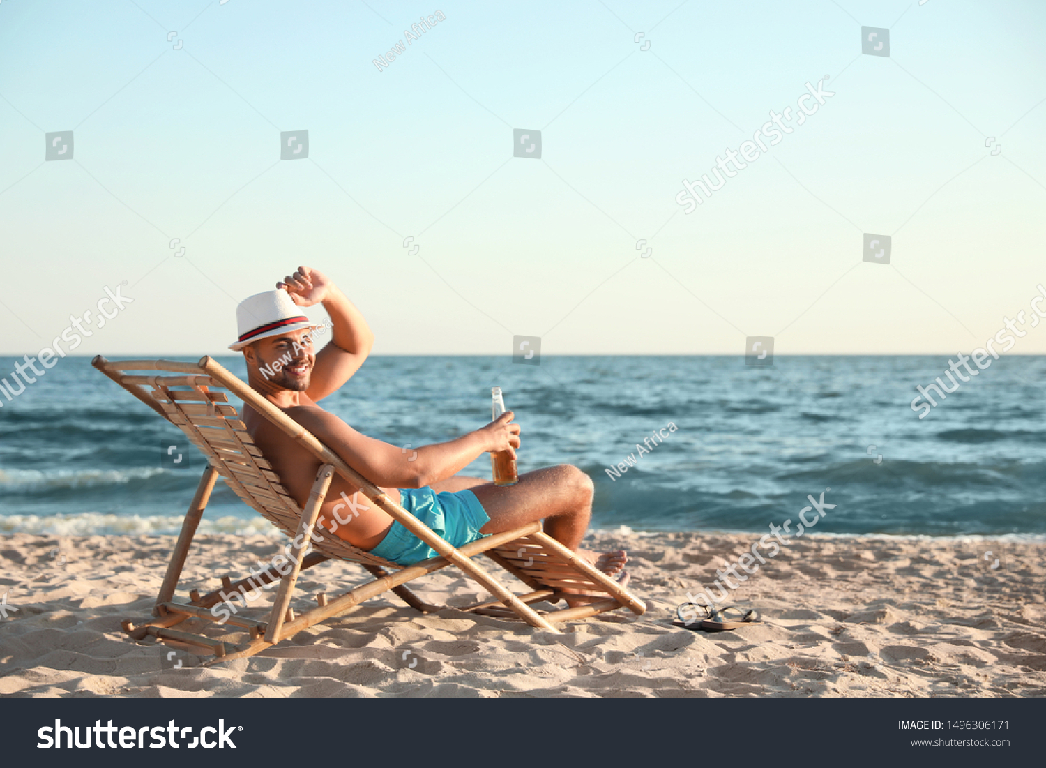 Young man relaxing in deck chair on beach near sea #1496306171