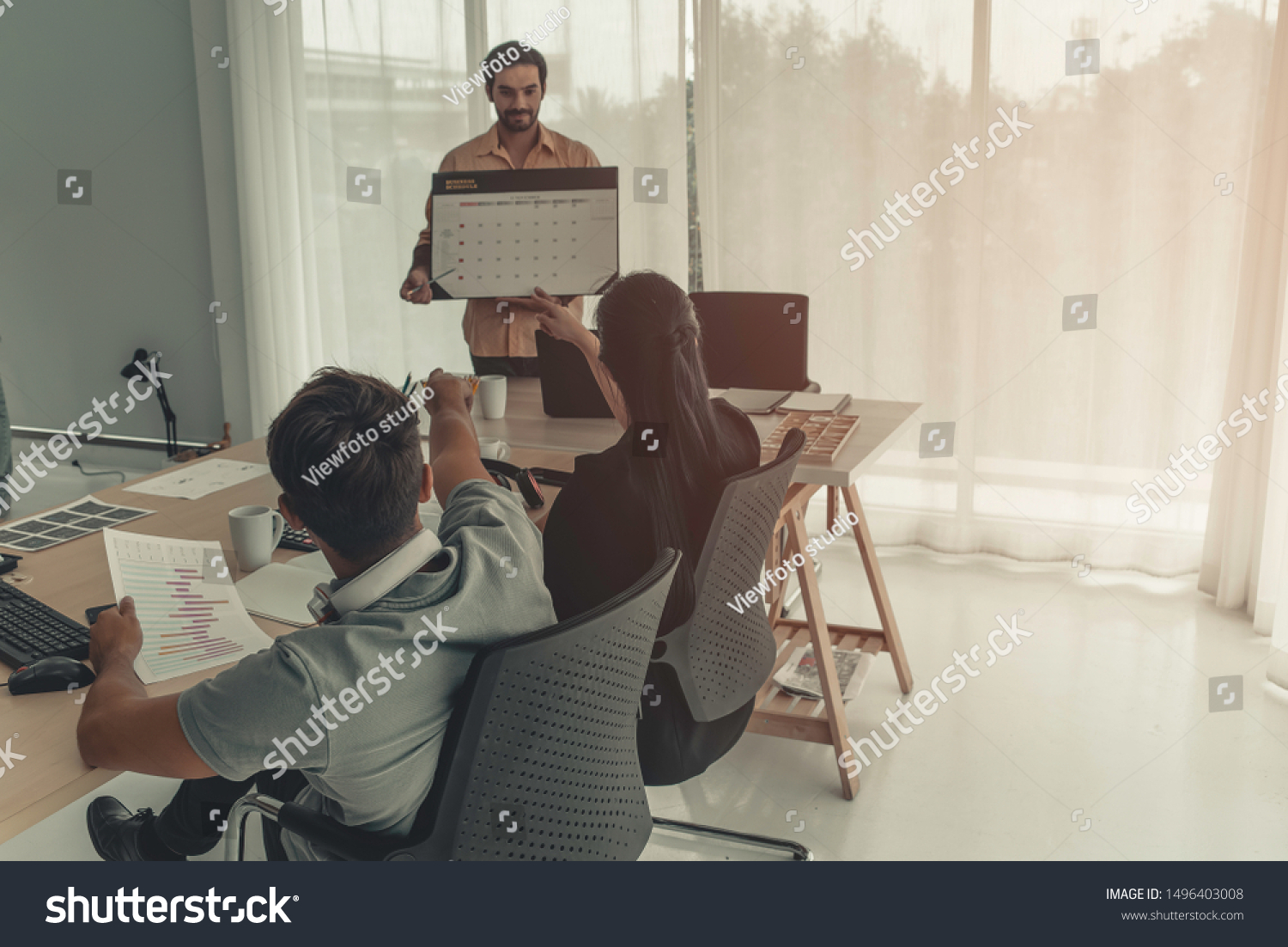 Hispanic businessman holding papers hands and smiling.Young team of coworkers making great business discussion in modern coworking office.Teamwork people concept.Horizontal, blurred background, flares #1496403008