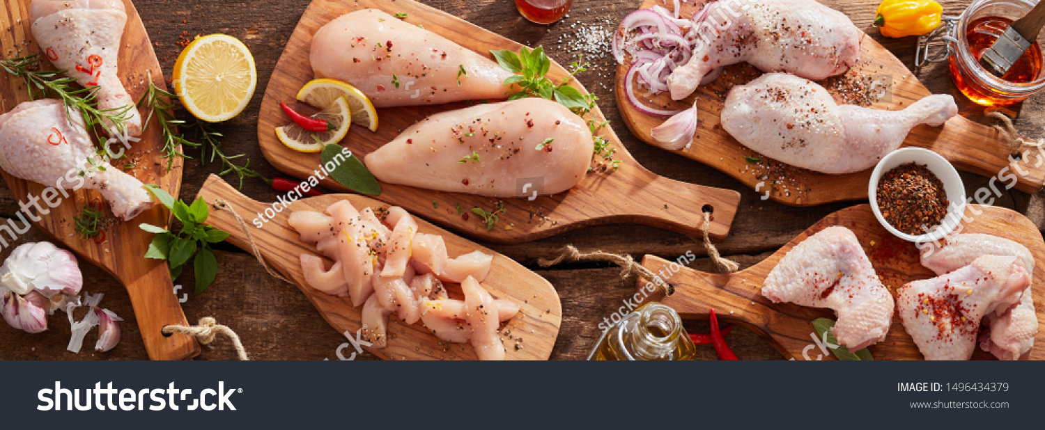 Panorama banner of raw chicken portions for cooking and barbecuing with skinless breasts and diced strips for goulash or stir fry with legs and wings with skin viewed from above with fresh seasoning #1496434379