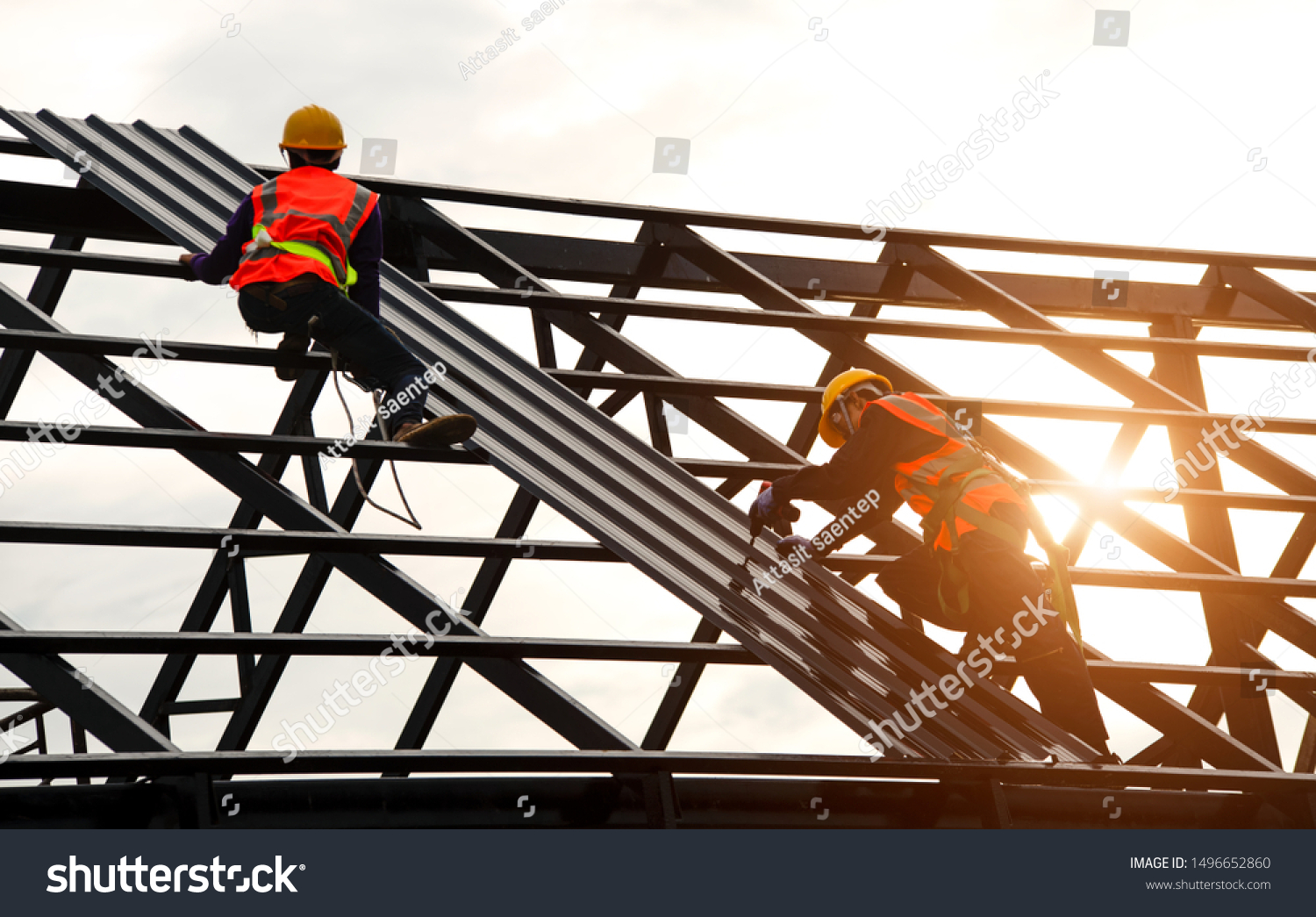 Construction engineer wear safety uniform using an electric drill and screw tools to fasten down metal roofing work for roof industrial concept with copy space #1496652860