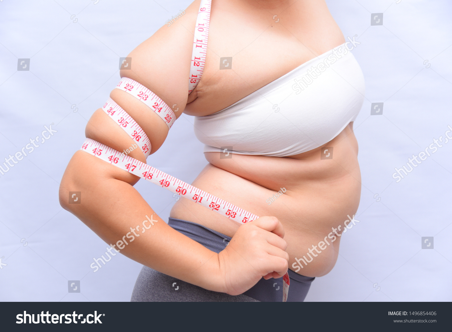 Beautiful fat woman She uses a tape measure to measure her arms on a white background. She wants to lose weight the concept of surgery and break down the fat underneath. #1496854406