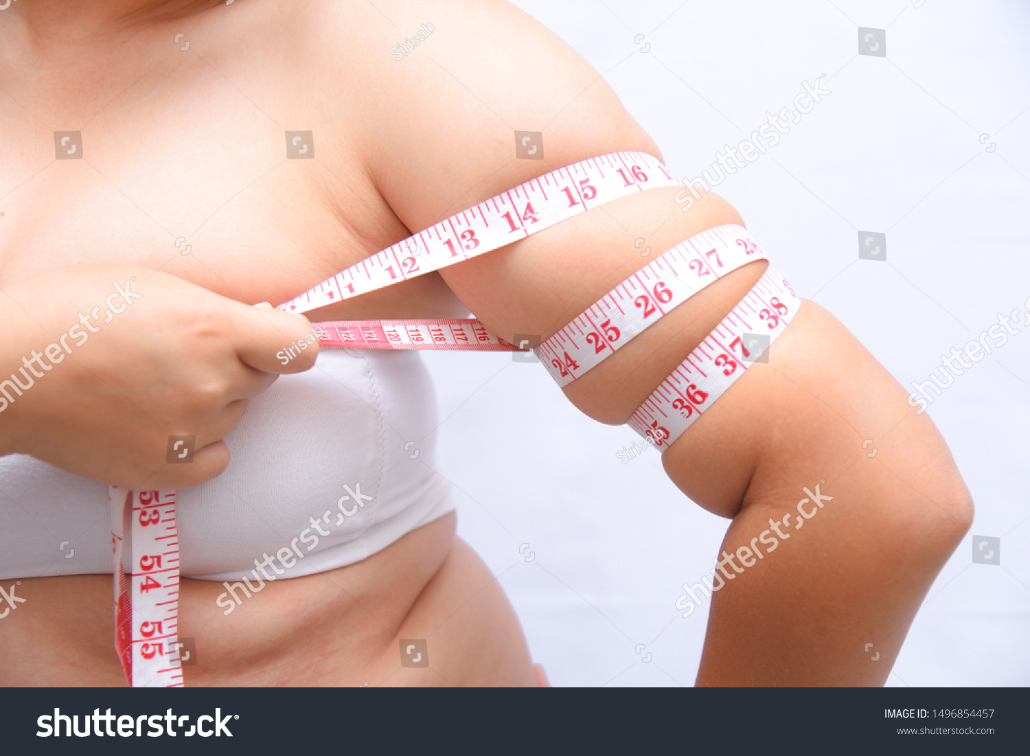 Beautiful fat woman She uses a tape measure to measure her arms on a white background. She wants to lose weight the concept of surgery and break down the fat underneath. #1496854457