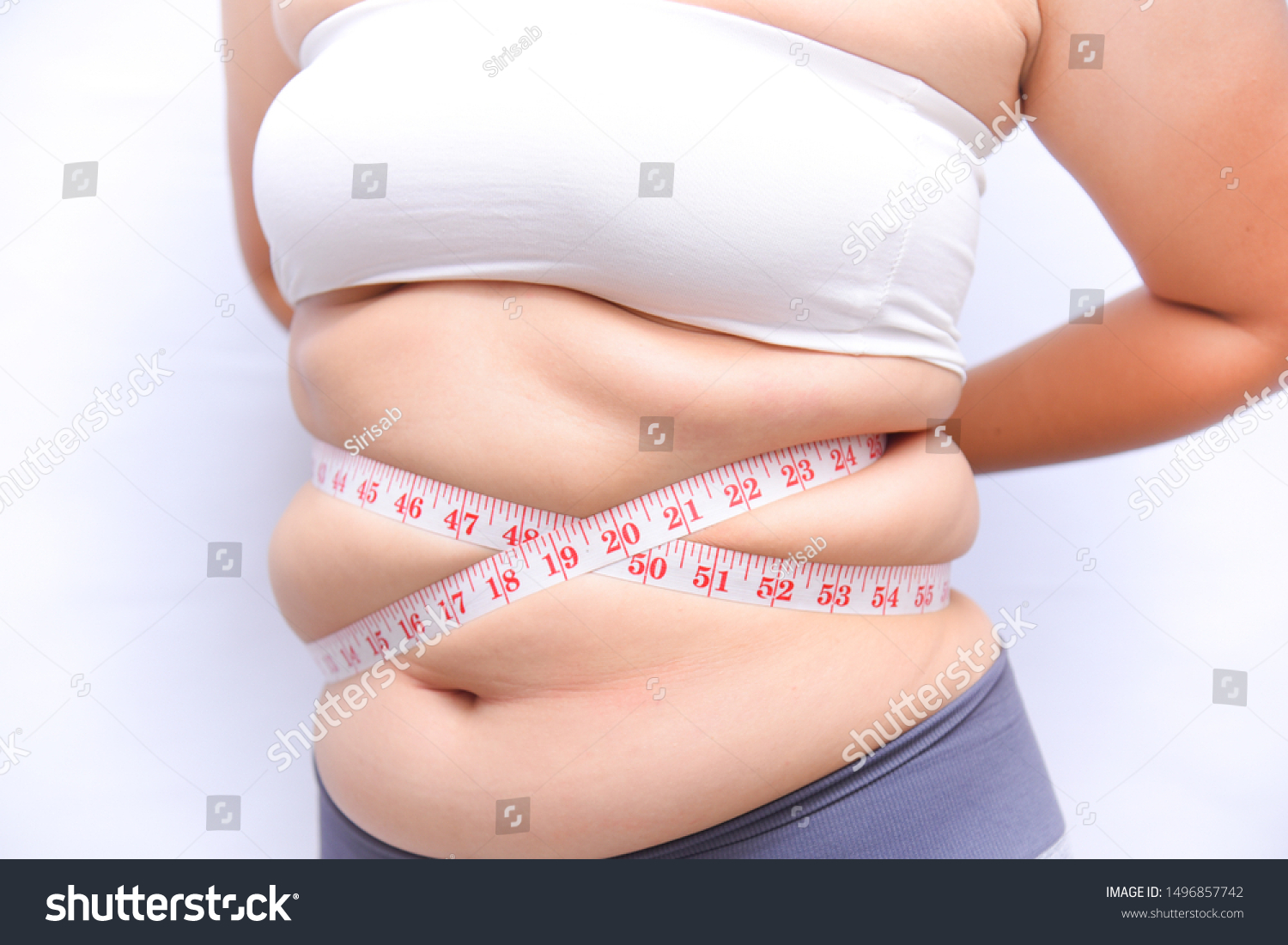 A beautiful fat woman with a tape measure, using her hands to hold the tape measure, the belly measure in the form of a cross on a white background She wants to lose weight the concept of surgery and. #1496857742