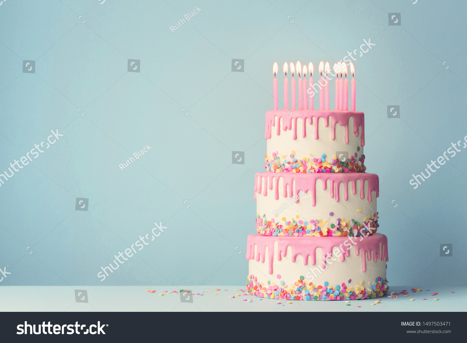 Tiered birthday cake with drip frosting and twelve candles #1497503471