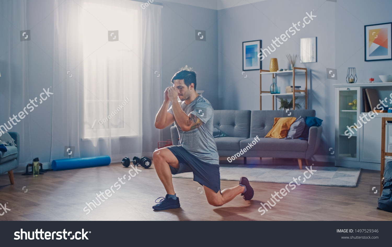 Strong Athletic Fit Man in T-shirt and Shorts is Doing Forward Lunge Exercises at Home in His Spacious and Bright Apartment with Minimalistic Interior. #1497529346