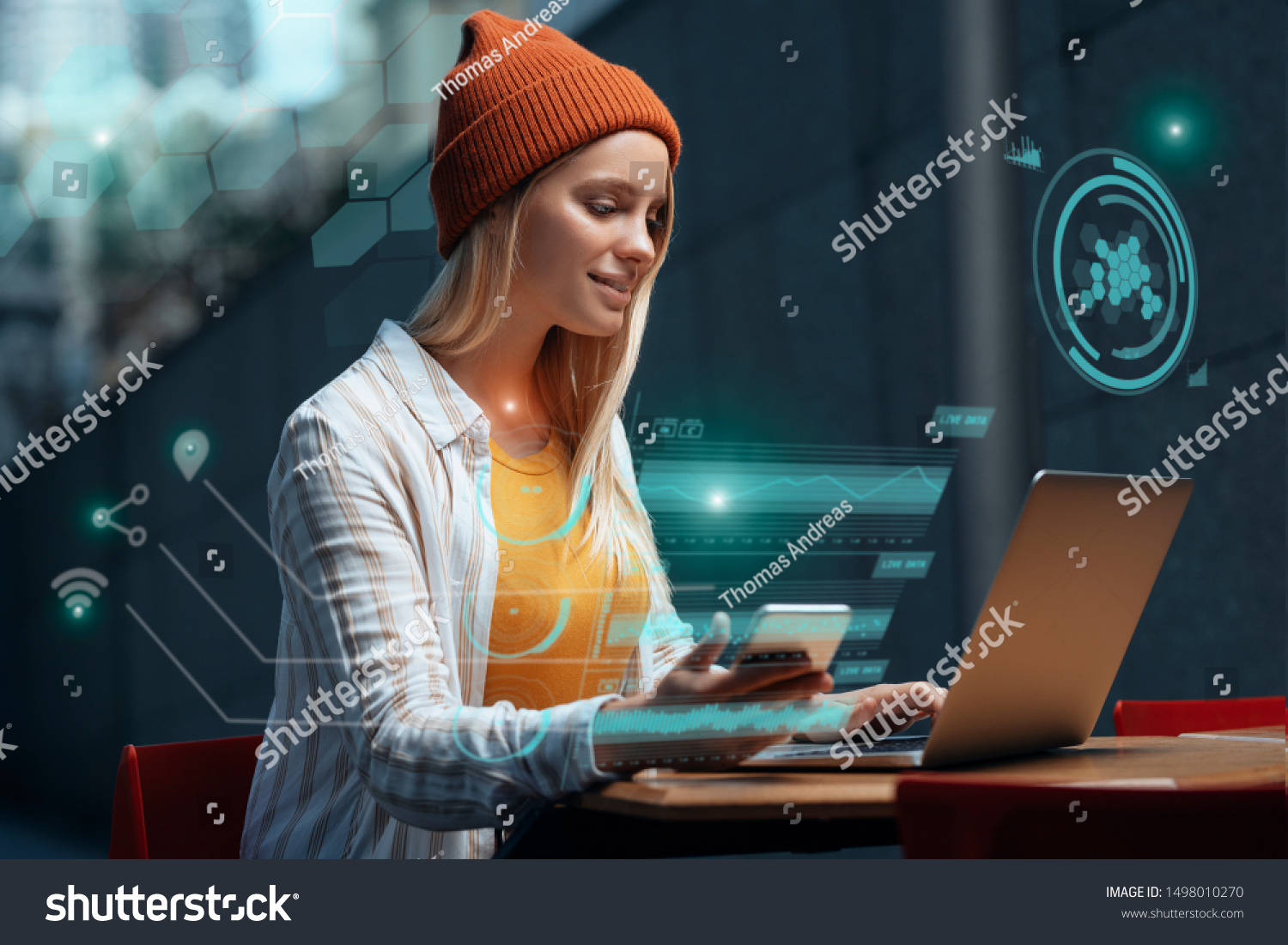Freelancers of the future could be working with a digital HUD around them. A millennial young woman is working with her laptop and phone in a cafe, while a holographic projection encircles her. #1498010270