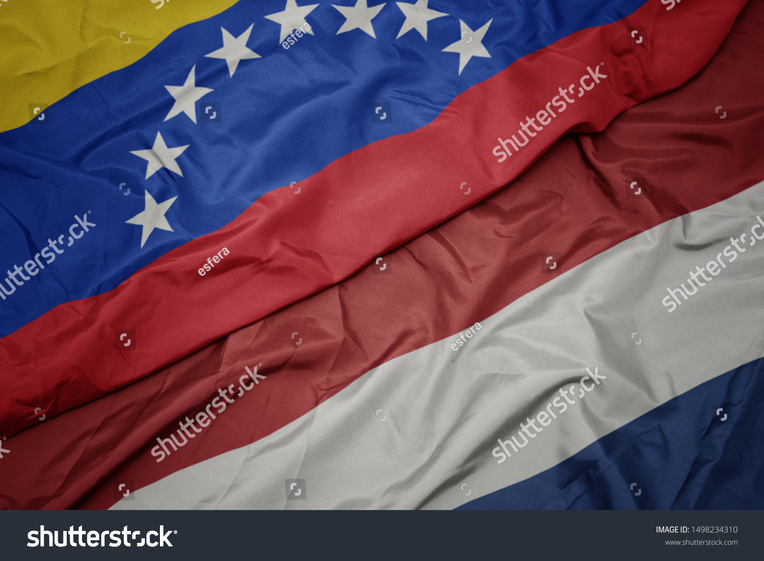 waving colorful flag of netherlands and national flag of venezuela. macro #1498234310