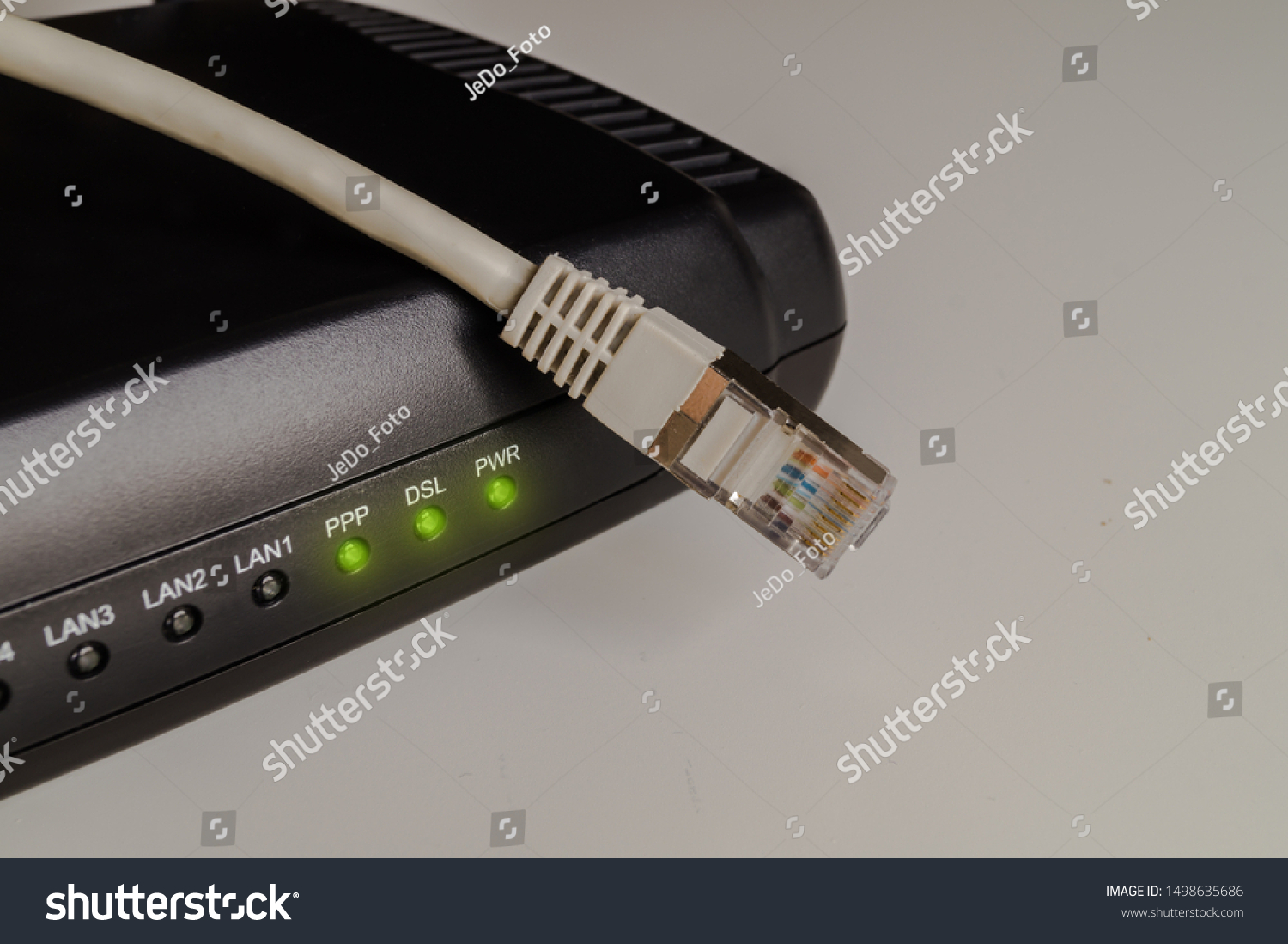 Black dsl modem or router with a network cable on a table. Concept picture for internet, wlan or mobil connections. #1498635686