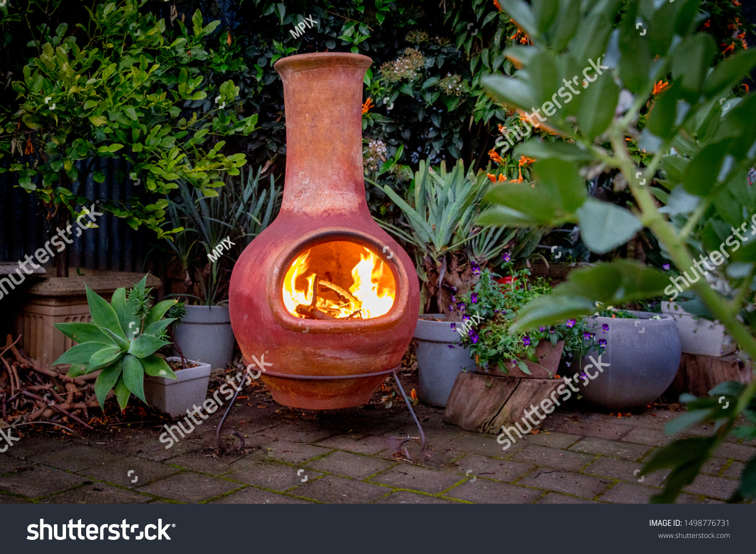 A Chimenea in the backyard.

A backyard fire place surrounded by plants. #1498776731