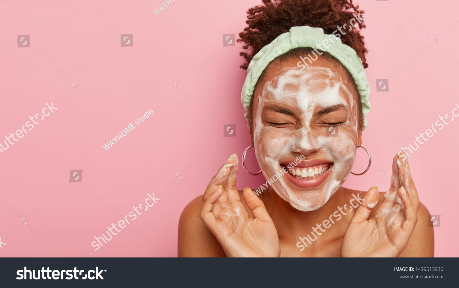 Attractive female model with crisp combed hair, closes eyes and gestures actively, feels pleased, washes face with cleansing foam, wears headband, wants to have well cared complexion and skin #1499513936