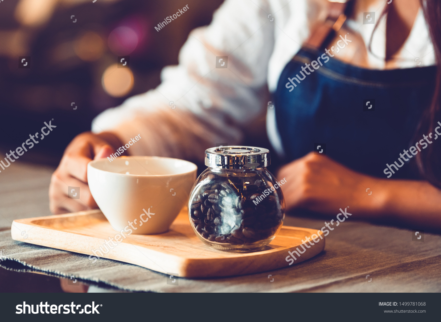 Closeup of professional female barista hand making and holding white cup of coffee. Happy young woman at counter bar in restaurant background. People lifestyles and Business occupation concept #1499781068